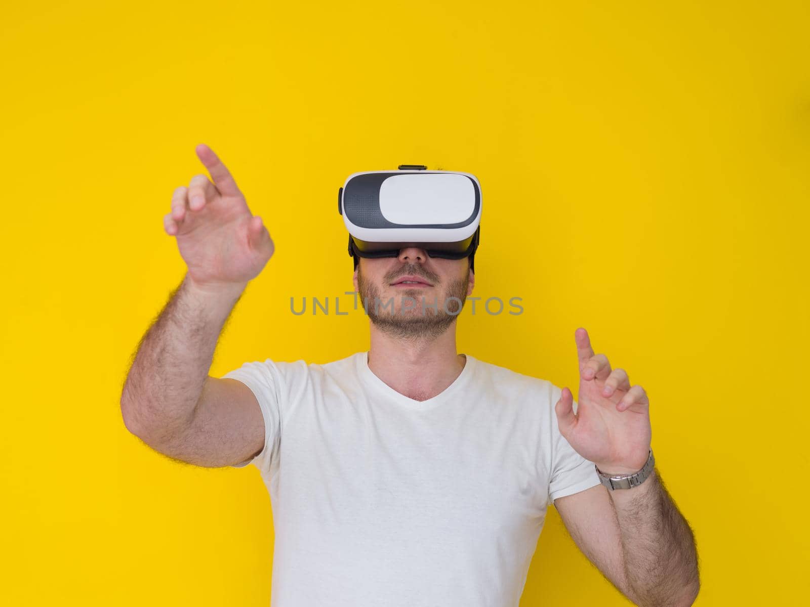 Happy man getting experience using VR headset glasses of virtual reality, isolated on yellow background