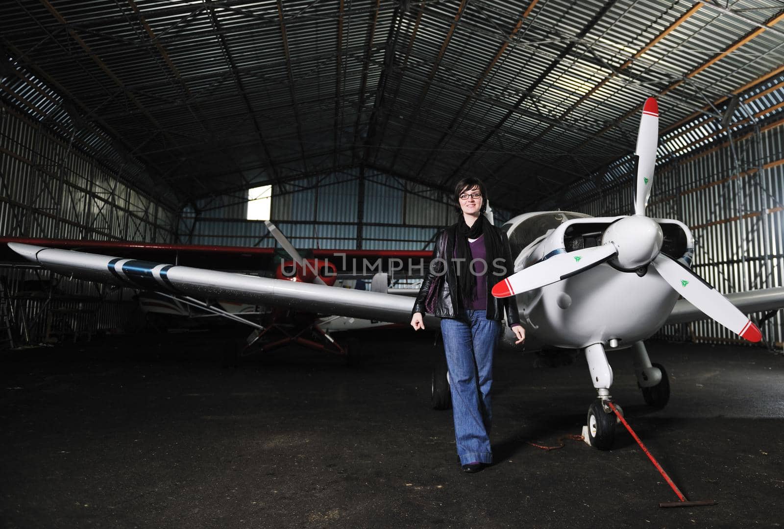 beautiful young woman model in fashion clothes posing in front of old private airplane 