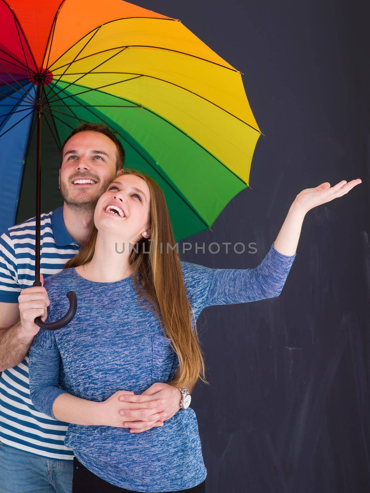 portrait of a beautiful loving young couple with a colorful umbrella isolated on a gray background