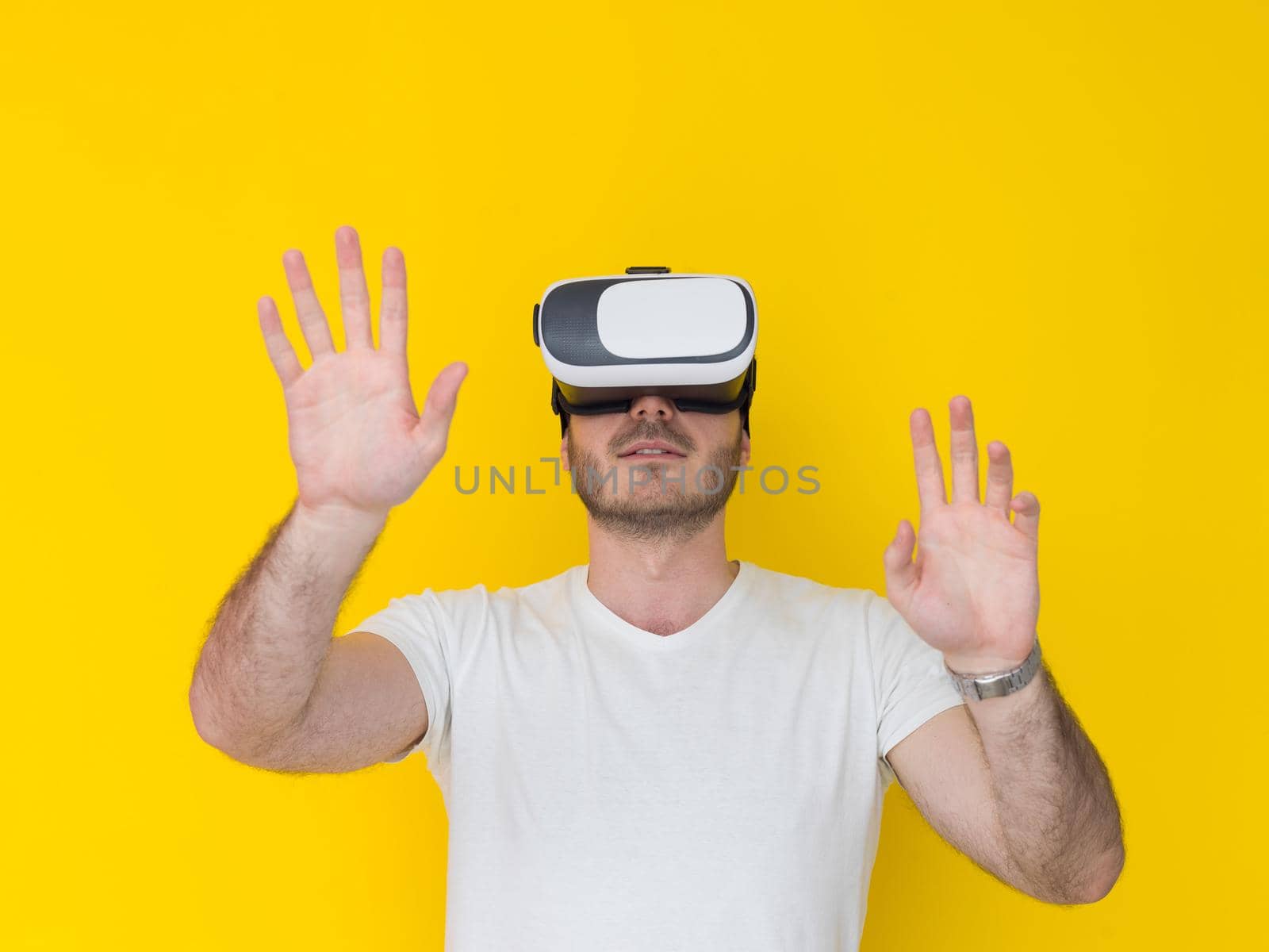 Happy man getting experience using VR headset glasses of virtual reality, isolated on yellow background