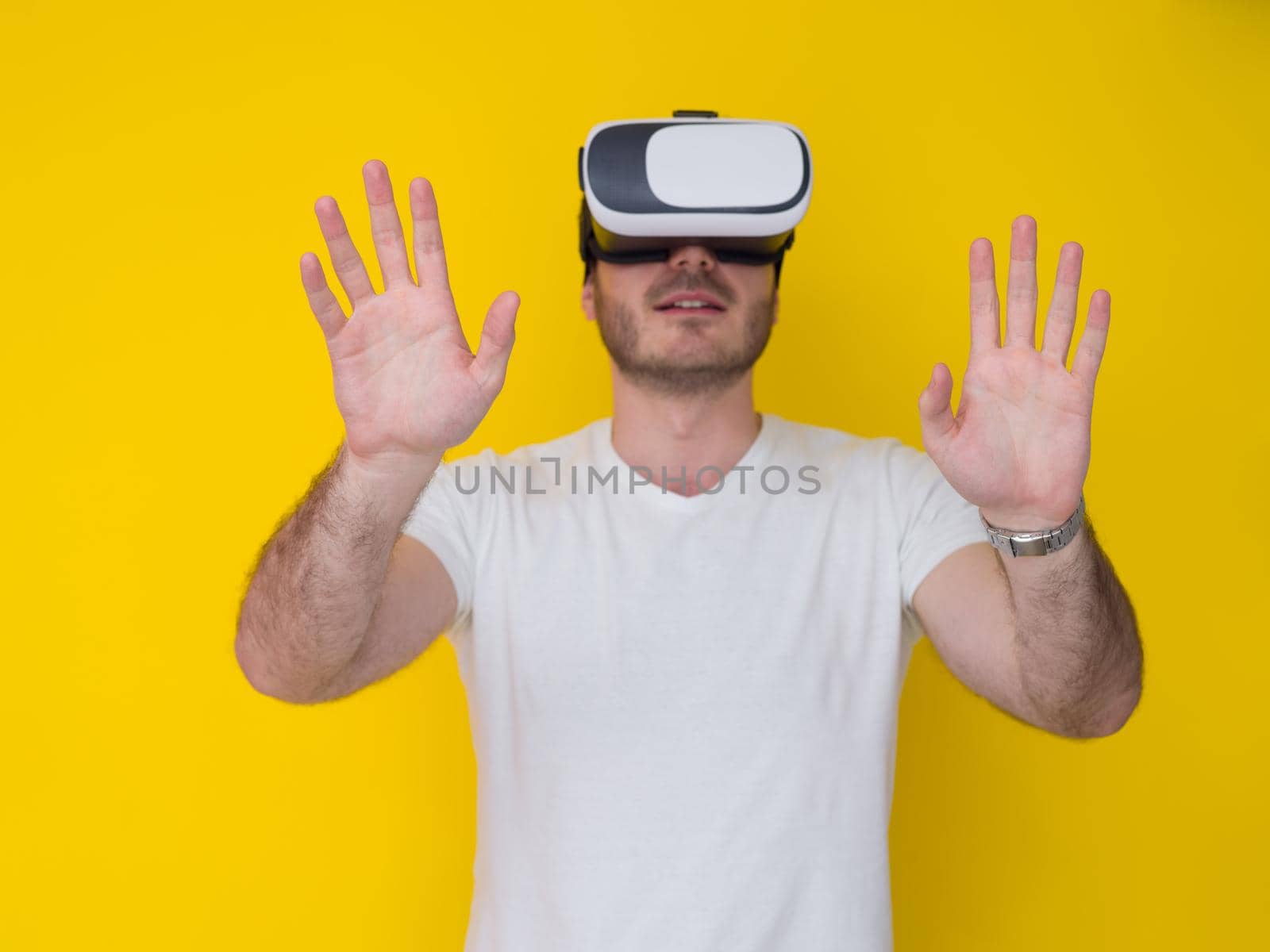 Happy man getting experience using VR headset glasses of virtual reality, isolated on yellow background