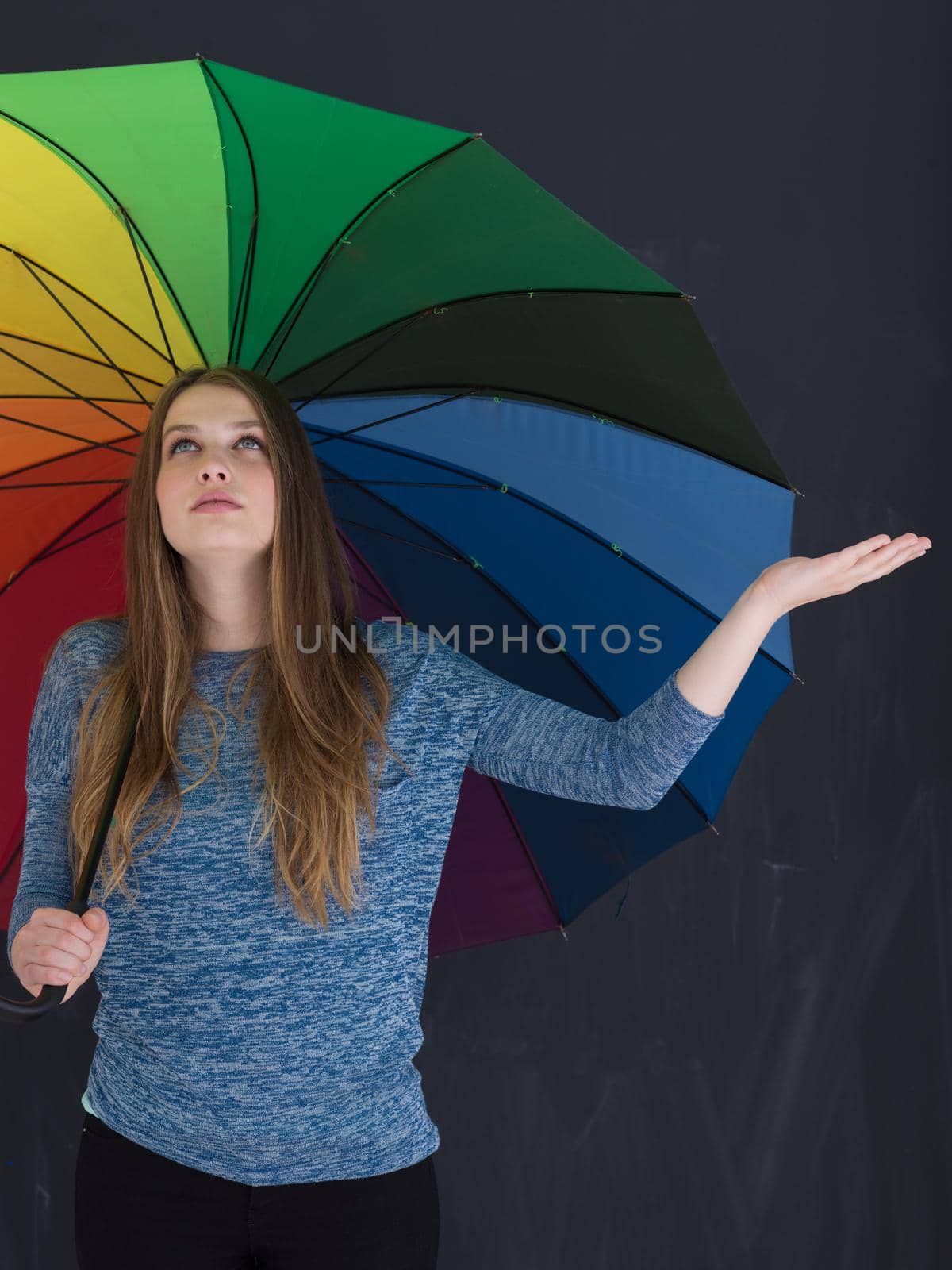 portrait of a young handsome woman with a colorful umbrella isolated on a gray background