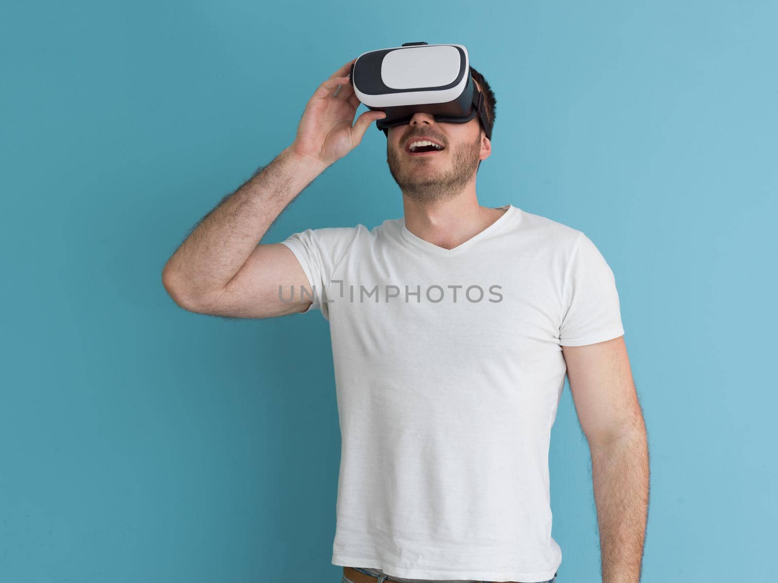Happy man getting experience using VR headset glasses of virtual reality, isolated on blue background
