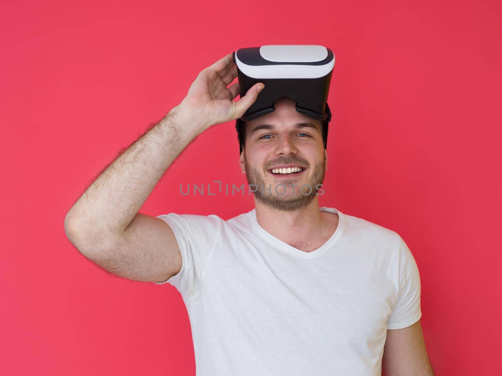 Happy man getting experience using VR headset glasses of virtual reality, isolated on red background