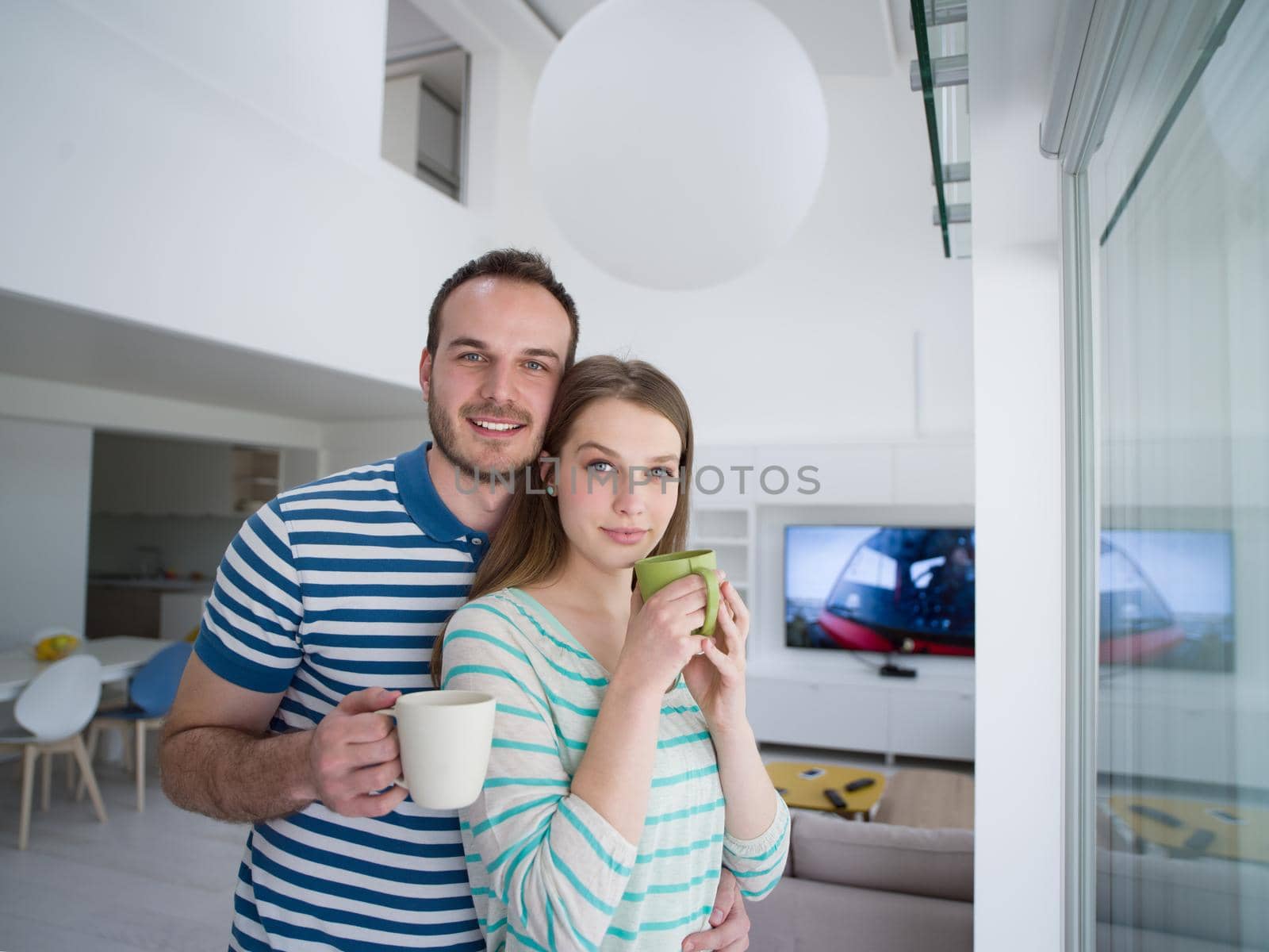 young beautiful handsome couple enjoying morning coffee at home