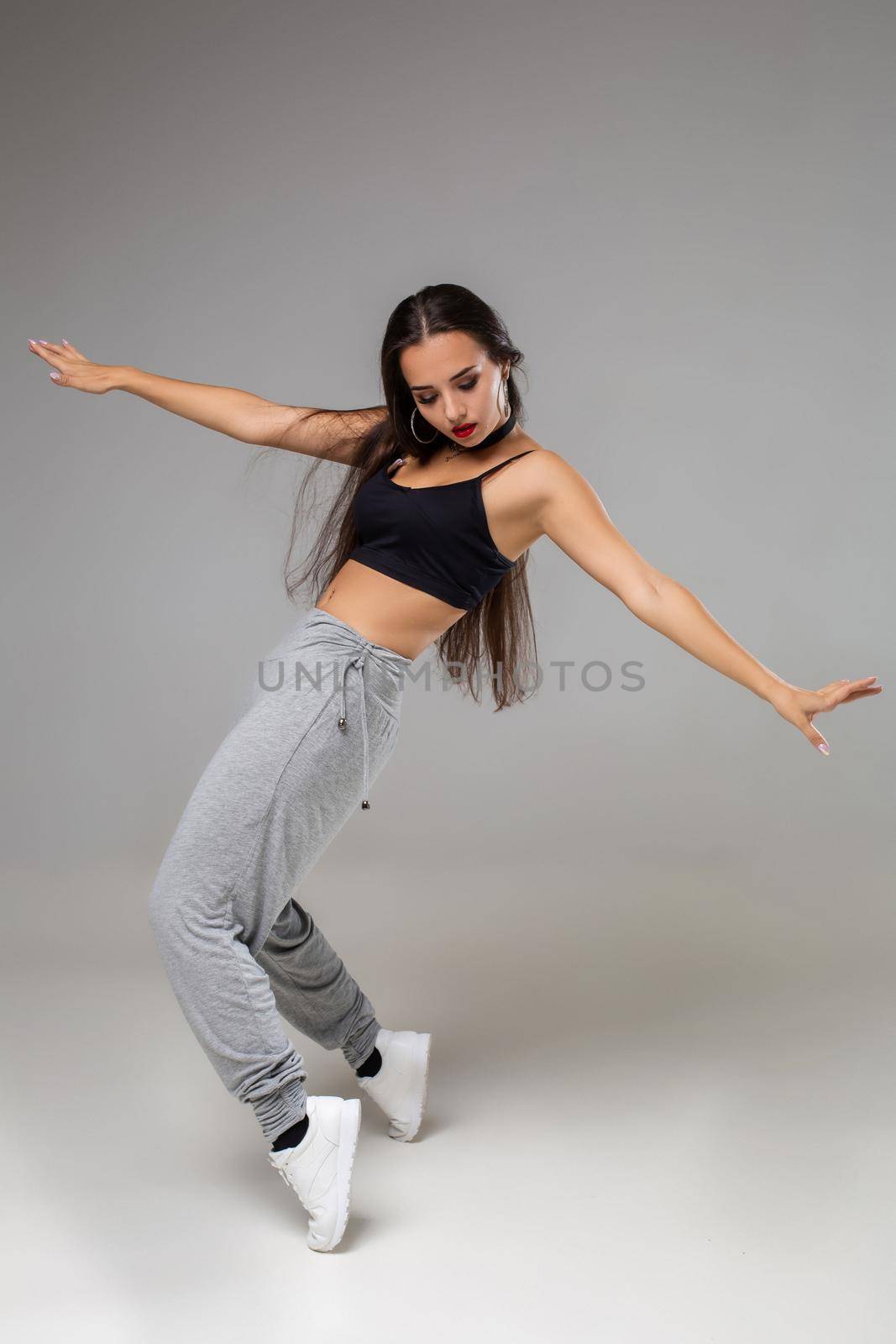 Modern dancer poses in front of the gray studio background. Modern dance styles, dancehall, jazz funk, hip hop