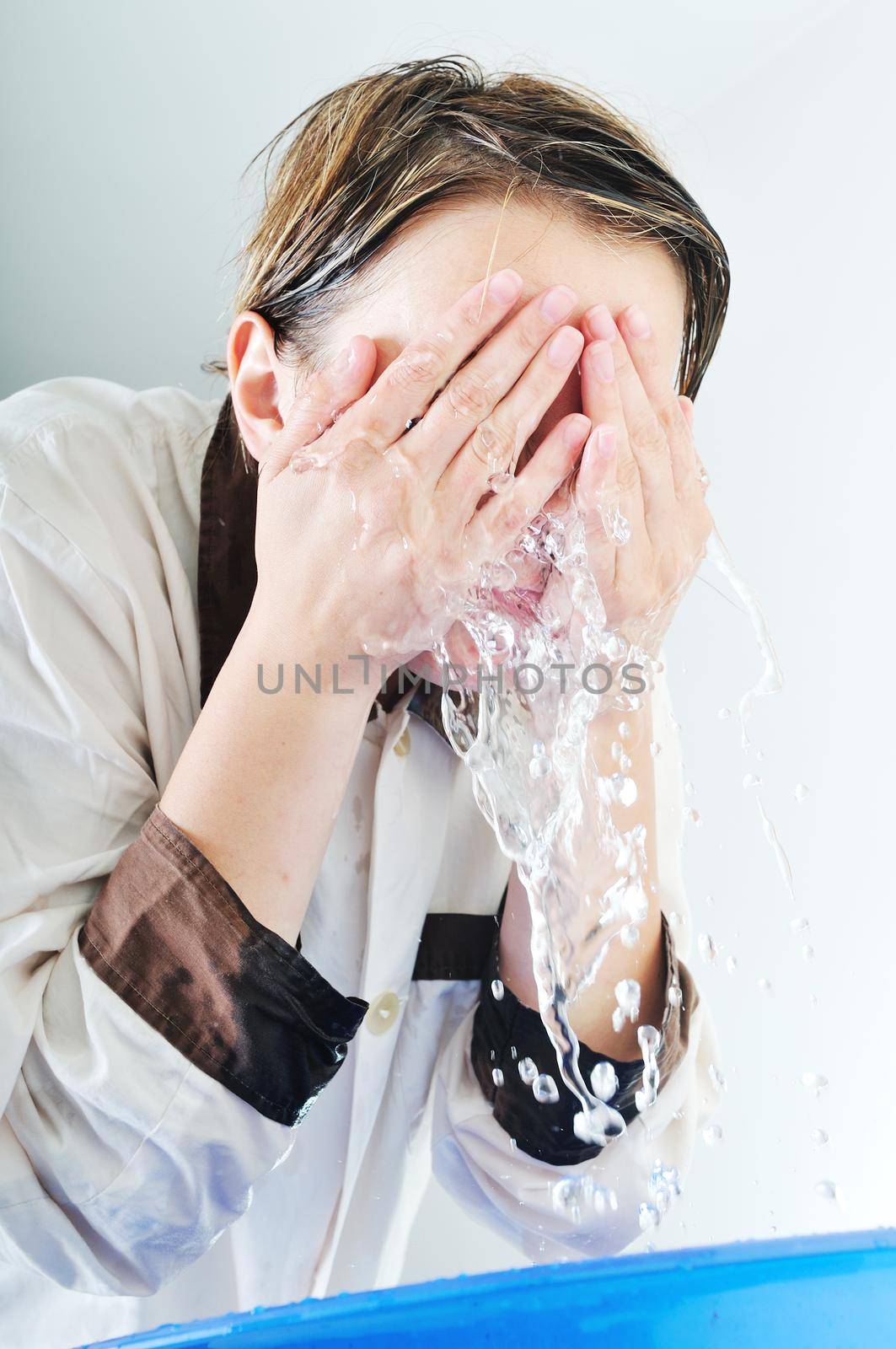 bautiful young woman wash face with clean water isolated on white in studio