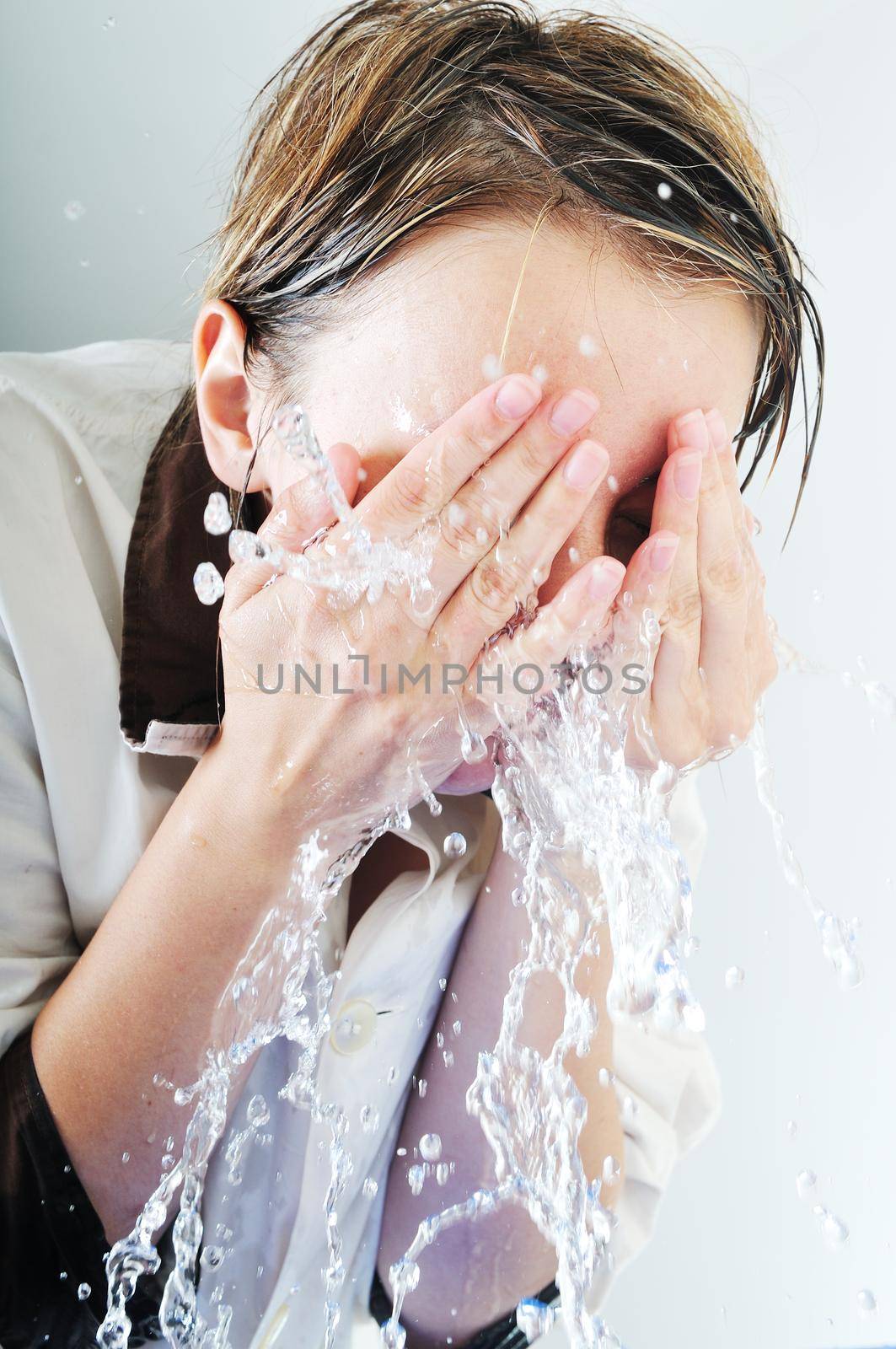 bautiful young woman wash face with clean water isolated on white in studio