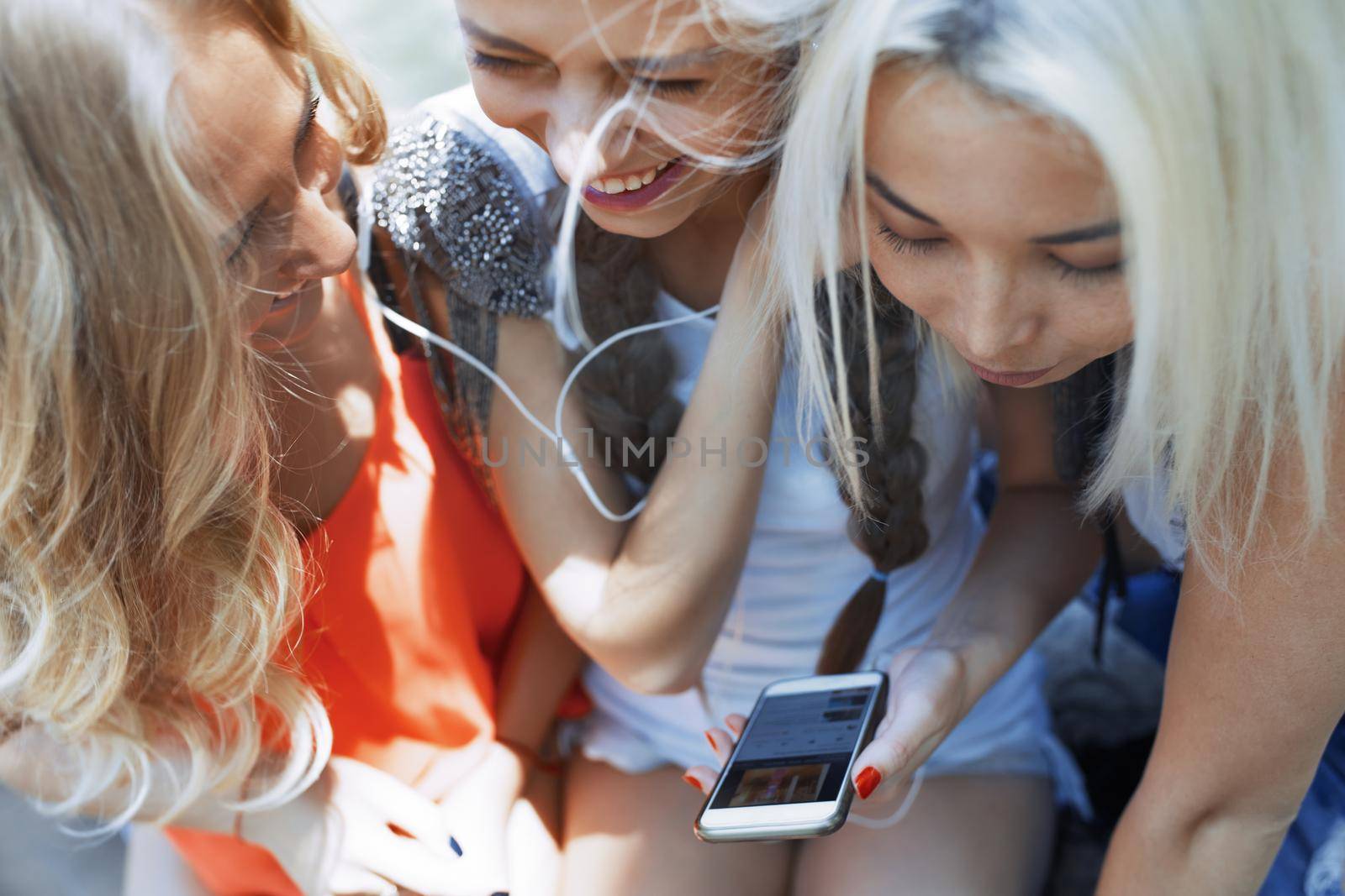 Three female friends with smartphone having fun in social media by Novic