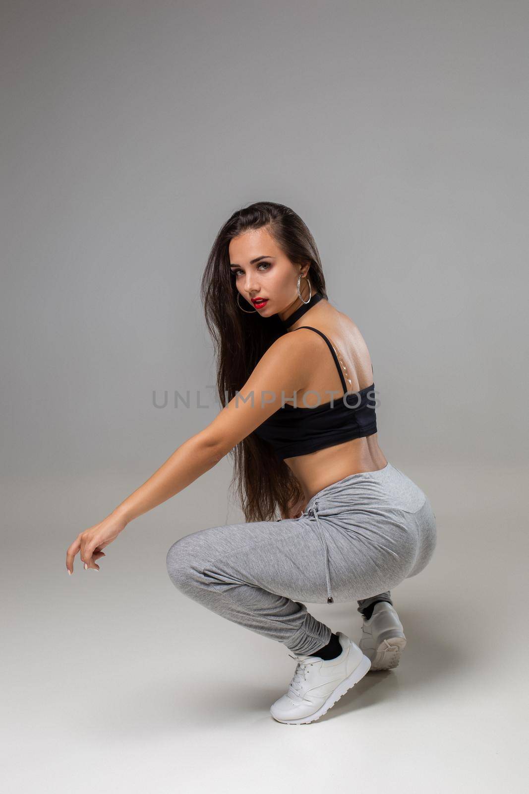 Modern dancer poses in front of the gray studio background. Modern dance styles, dancehall, jazz funk, hip hop
