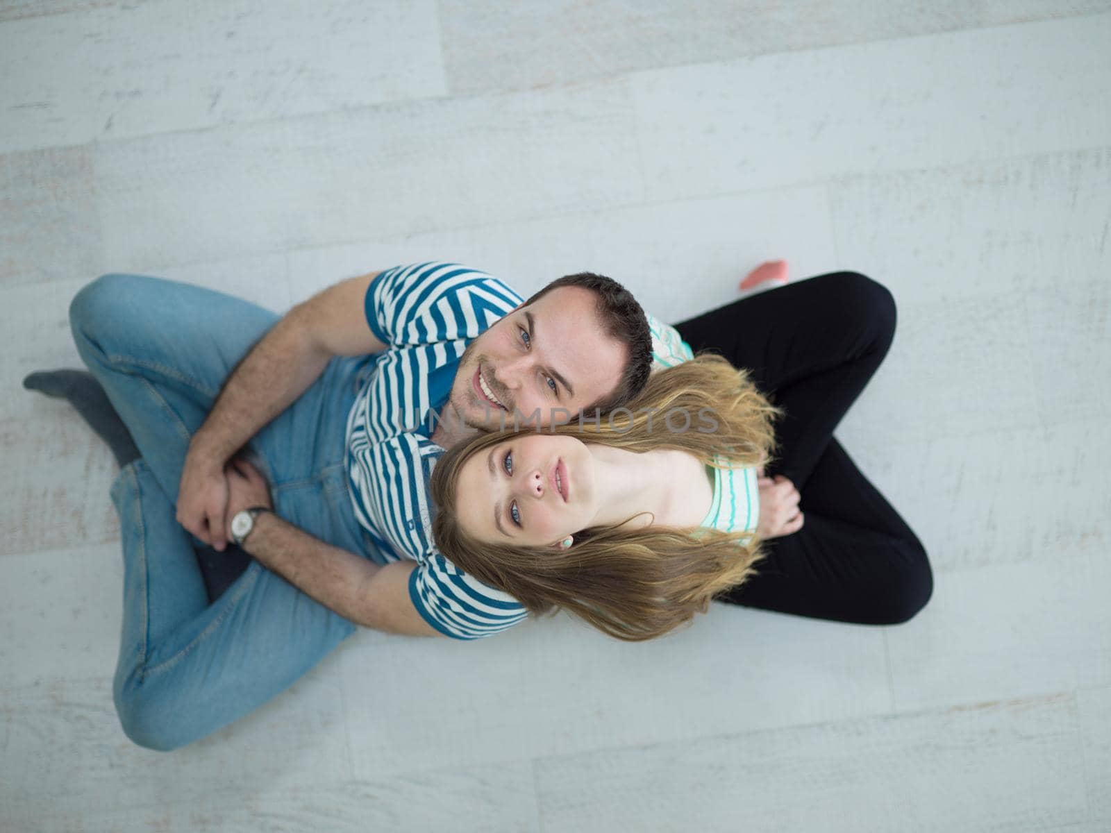 top view of Cheerful young couple sitting with back to each other on floor