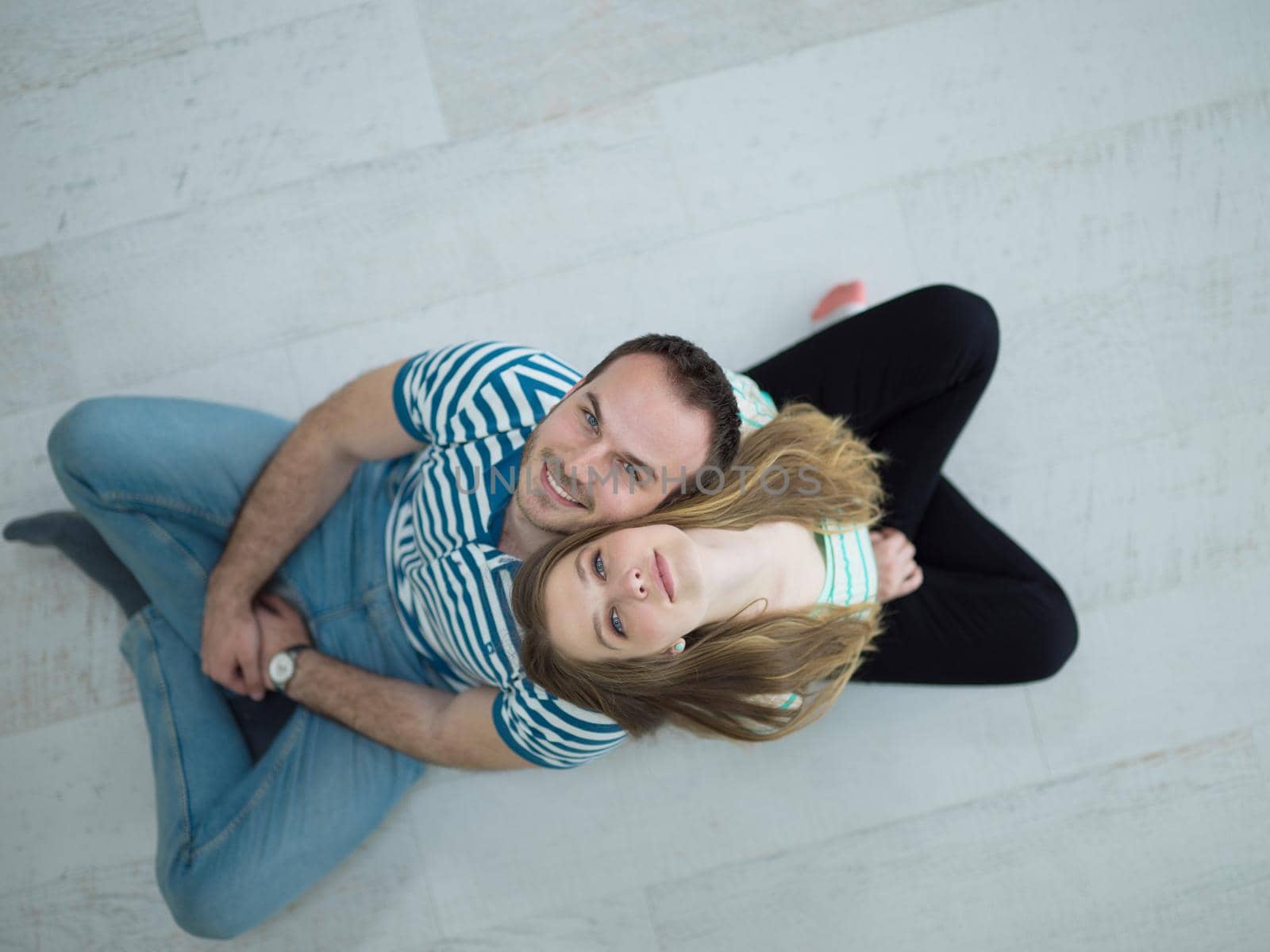 top view of Cheerful young couple sitting with back to each other on floor