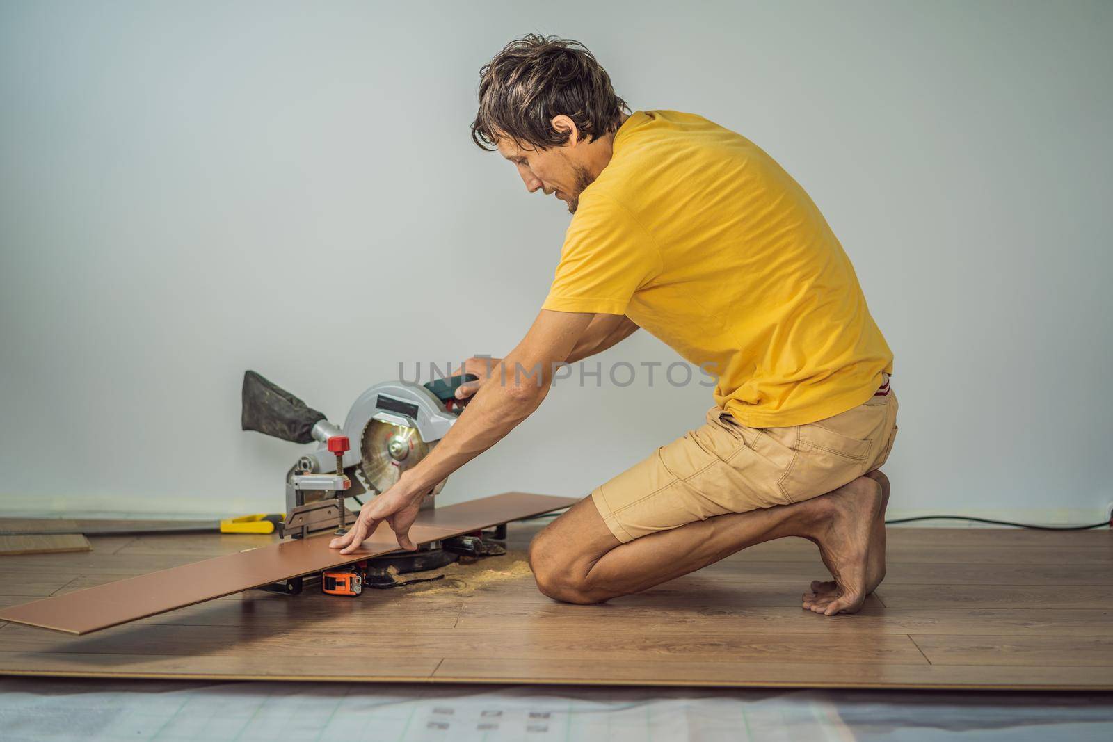 Man installing new wooden laminate flooring on a warm film floor. Infrared floor heating system under laminate floor.