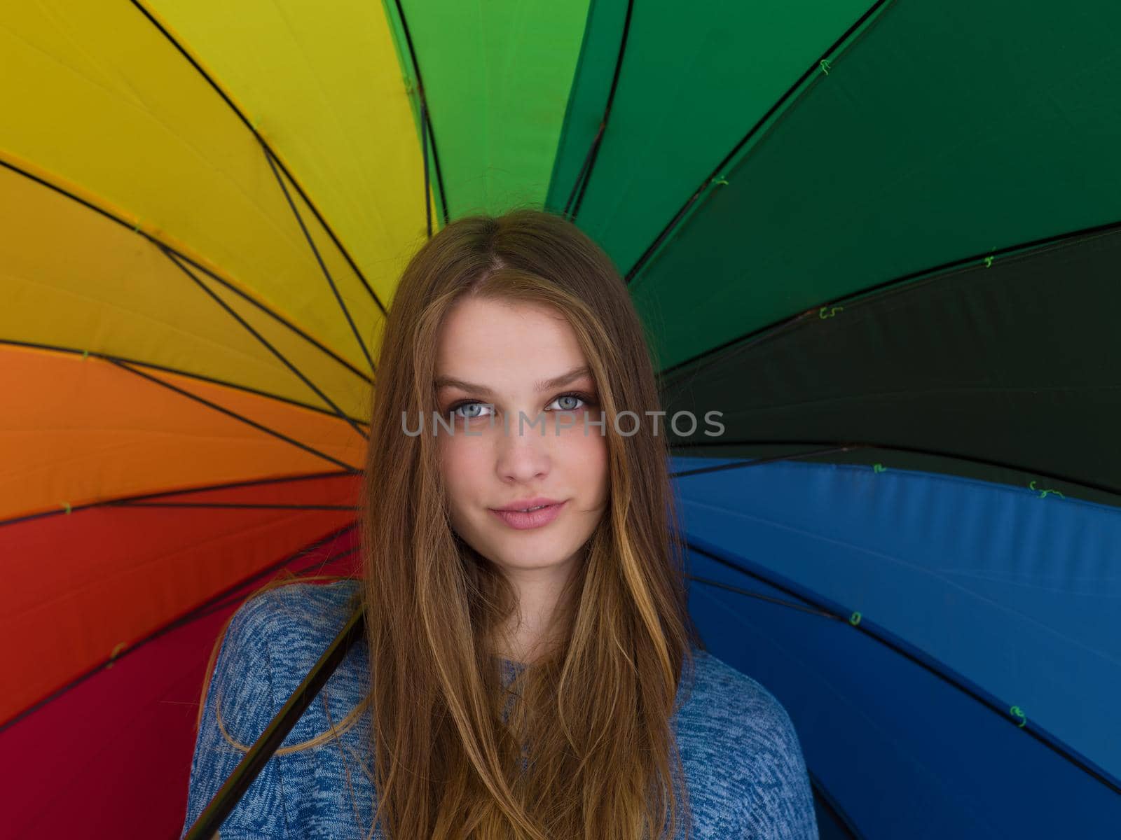 portrait of a young handsome woman with a colorful umbrella isolated on a gray background