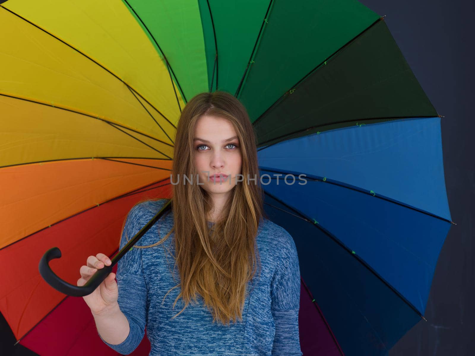 portrait of a young handsome woman with a colorful umbrella isolated on a gray background