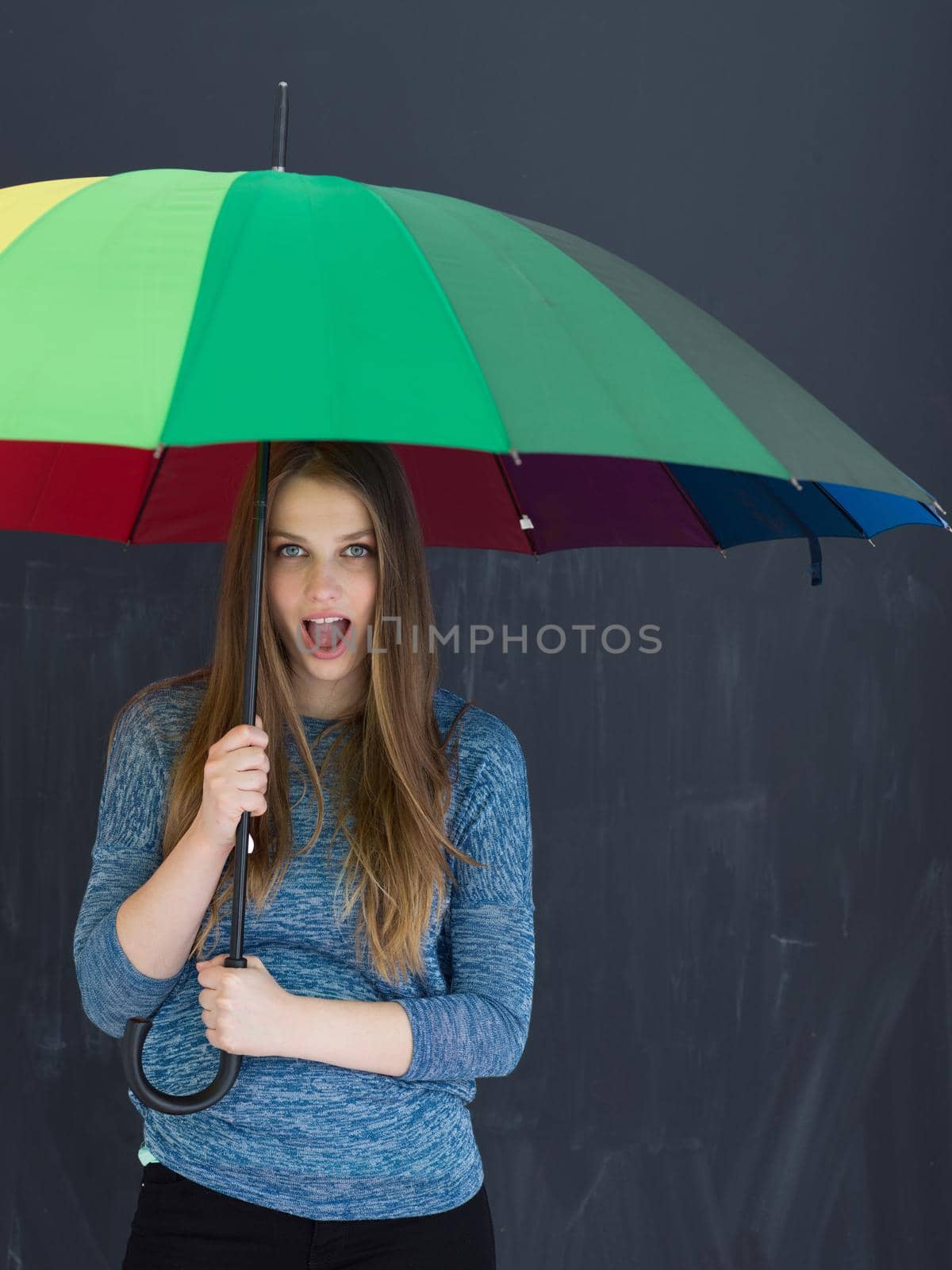 portrait of a young handsome woman with a colorful umbrella isolated on a gray background