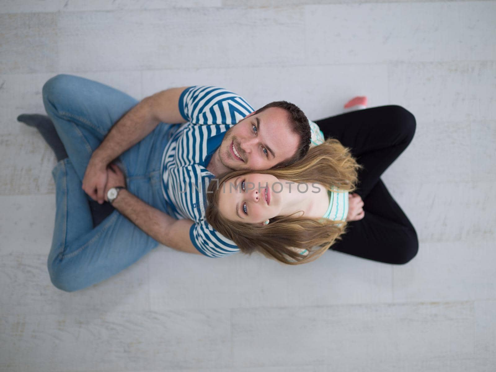 top view of Cheerful young couple sitting with back to each other on floor