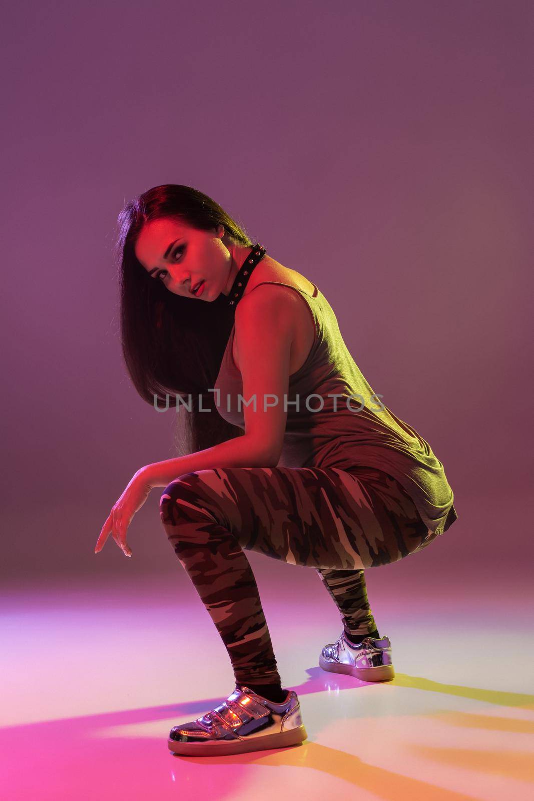 Attractive young blonde woman in the studio dancing Booty dance on a pink background. Color filters