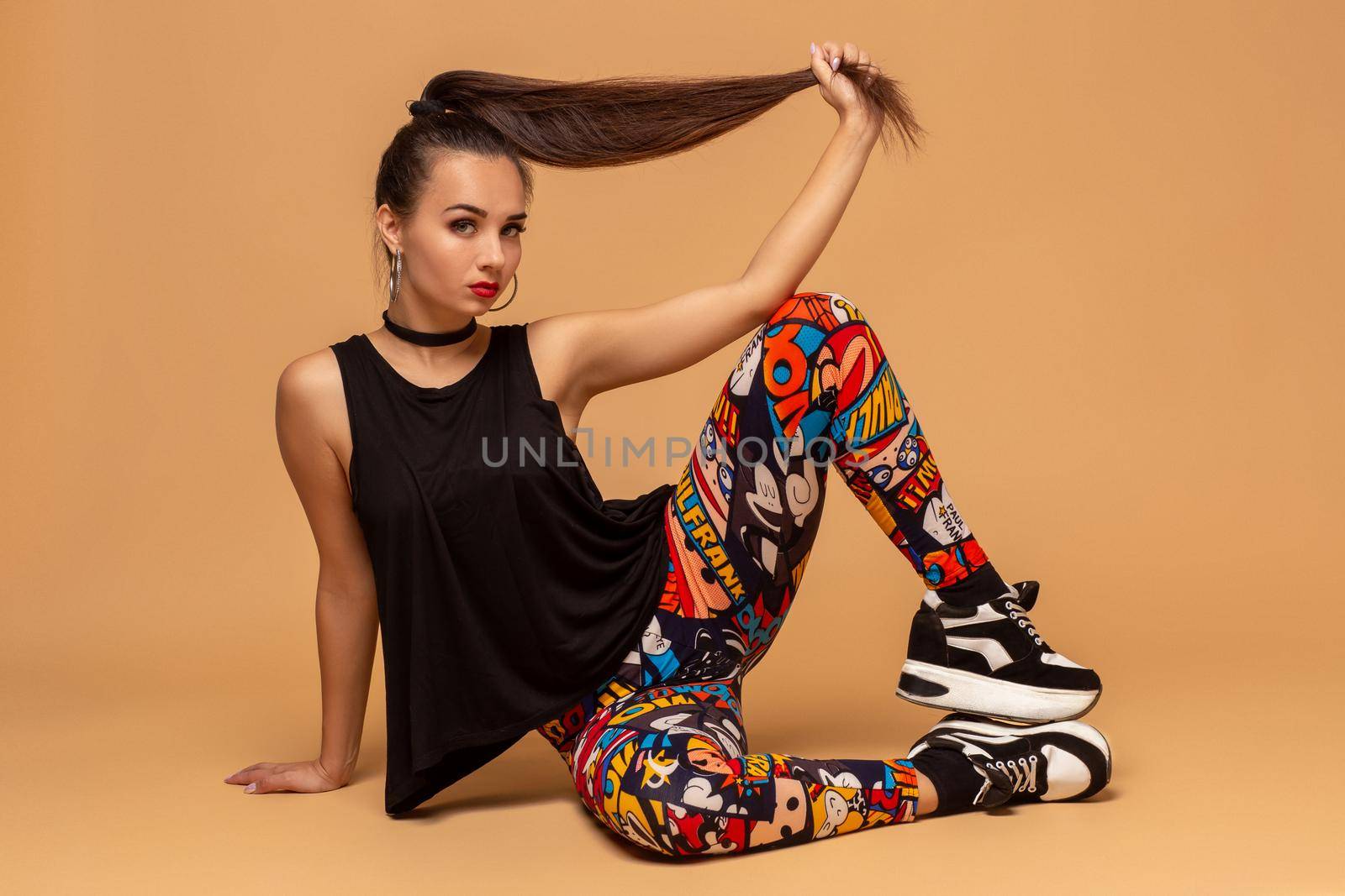 Young female dancer on studio background. Young modern style dancer girl sitting on floor in studio. Pretty female dancer of dancehall, jazz funk, hip hop