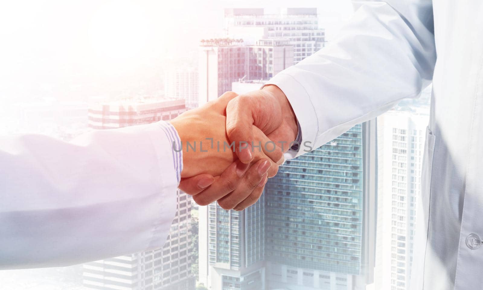 Close-up of the handshake between the two medics. Against the backdrop of the cityscape