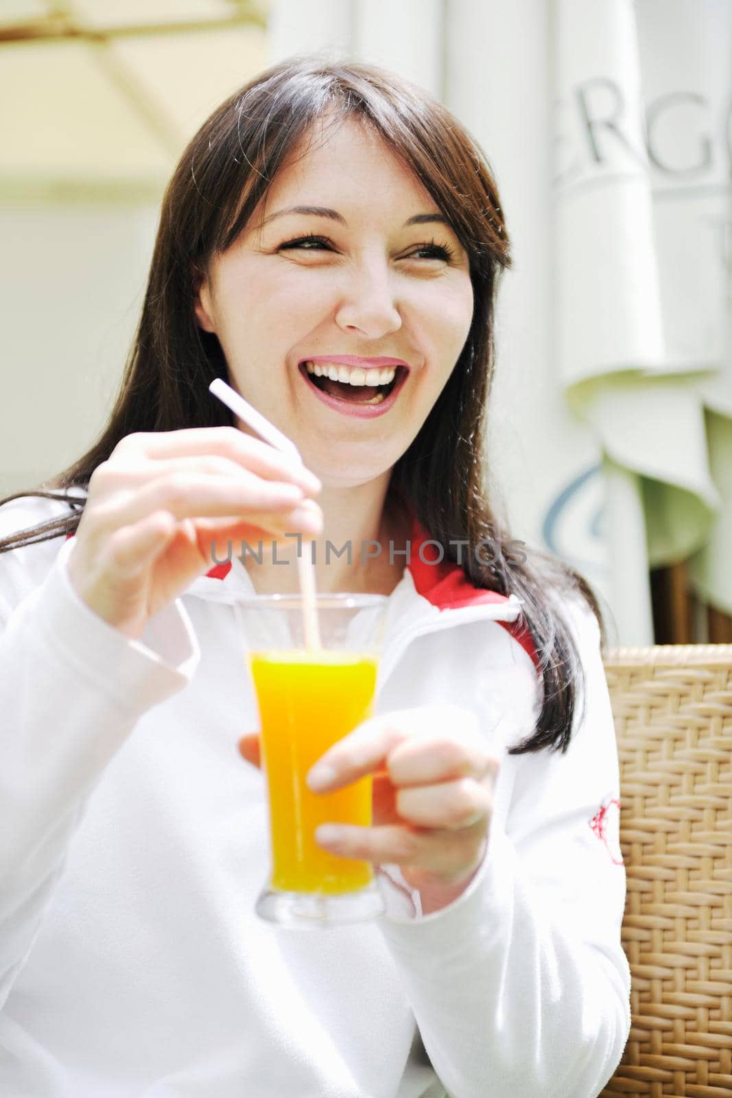 young woman drink juice outdoor in bright restaurant garden at spring