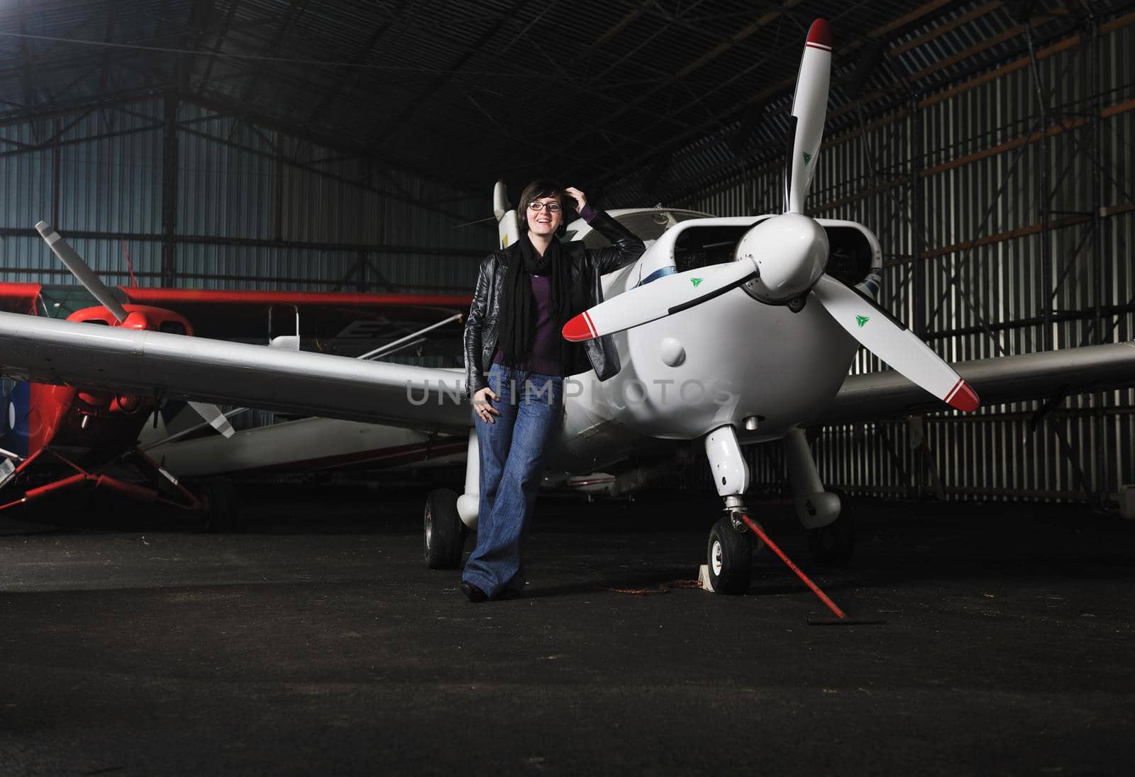 beautiful young woman model in fashion clothes posing in front of old private airplane 