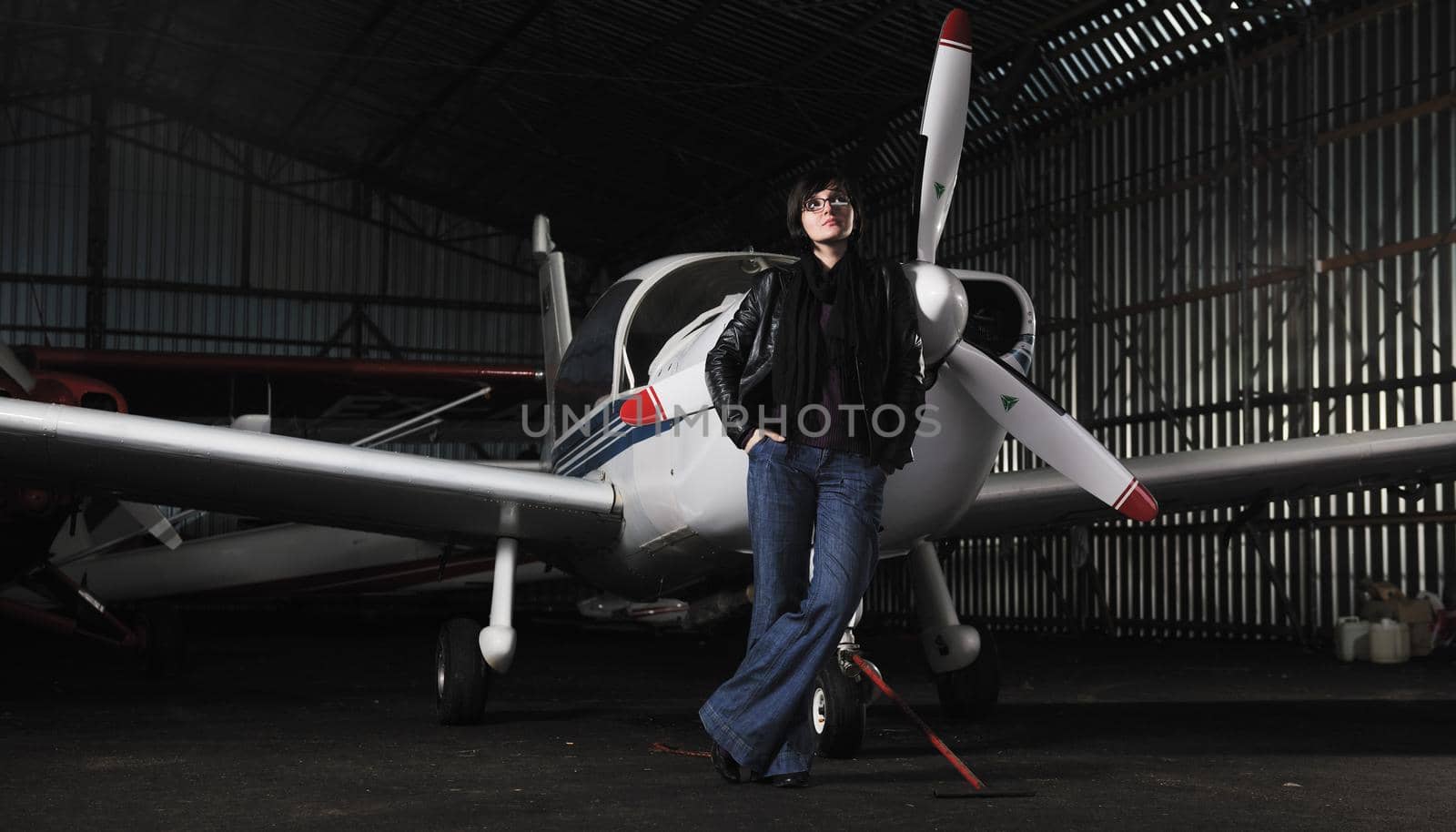 beautiful young woman model in fashion clothes posing in front of old private airplane 
