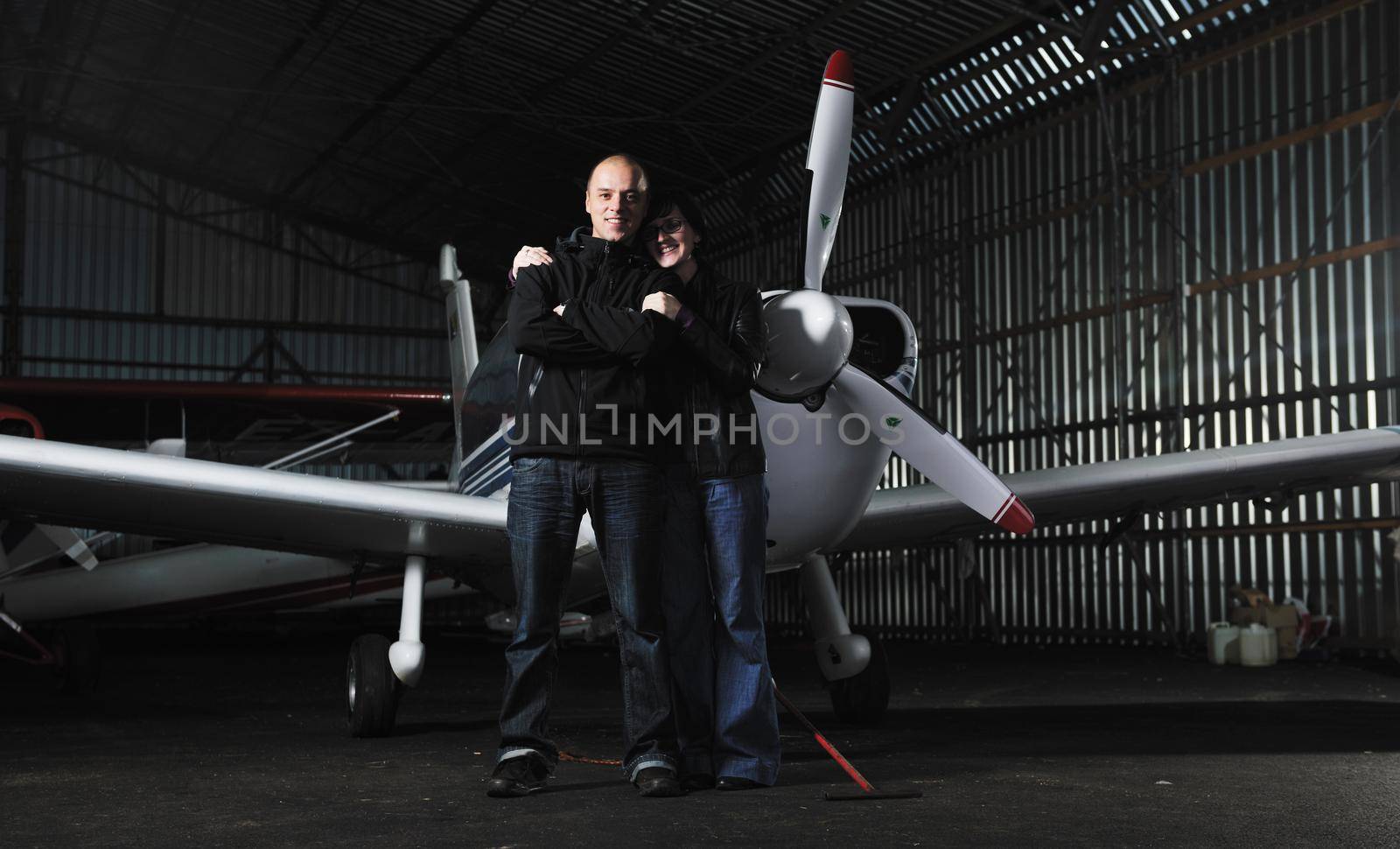 beautiful and happy young couple  posing in front of an old retro private propeler airplane and representing happines wealt and rich life concept