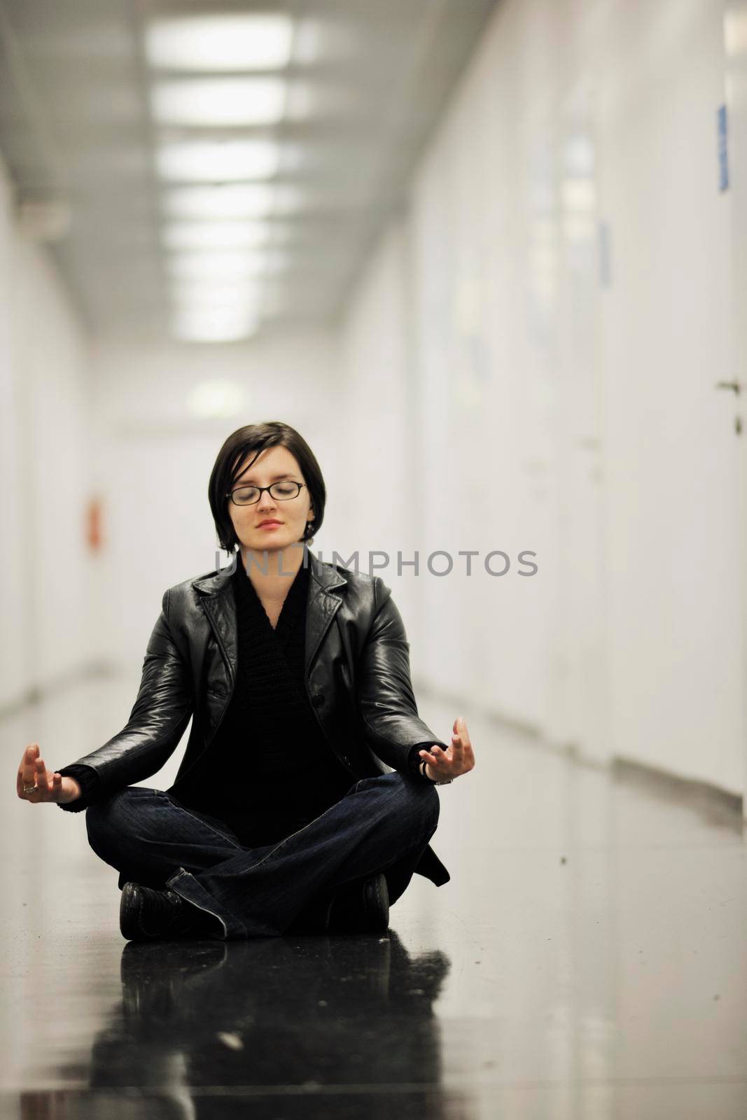 young casual woman sitting and precticing yoga indoor on abstract location