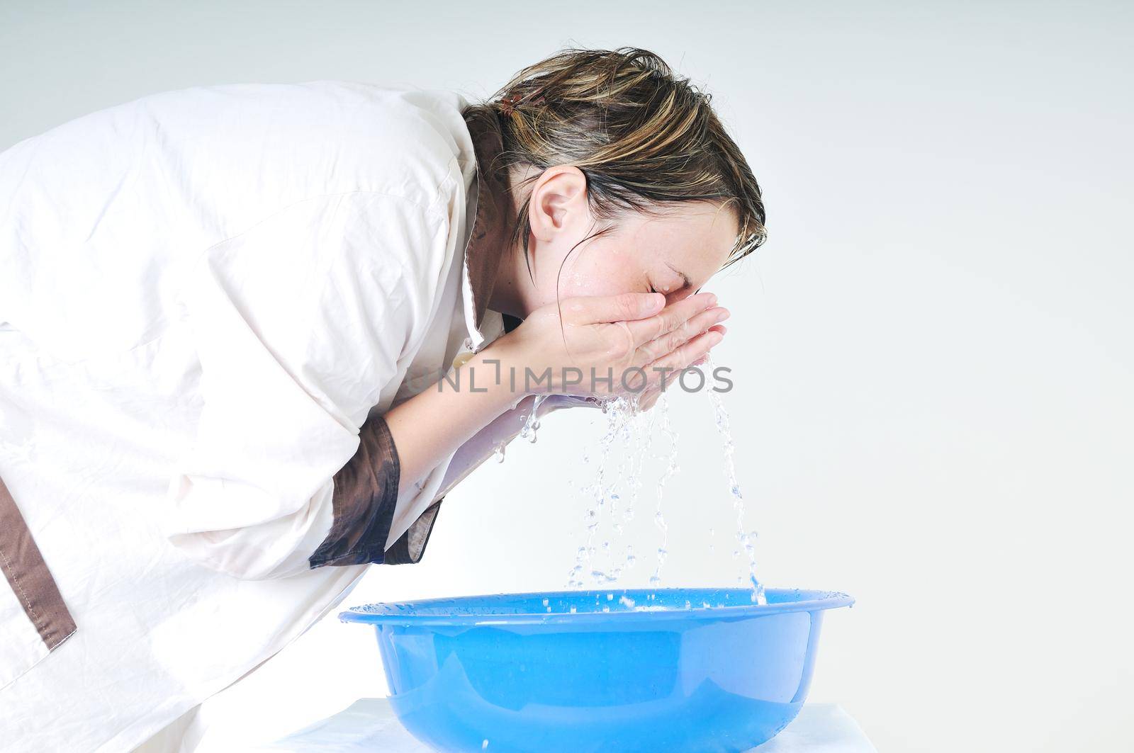 bautiful young woman wash face with clean water isolated on white in studio