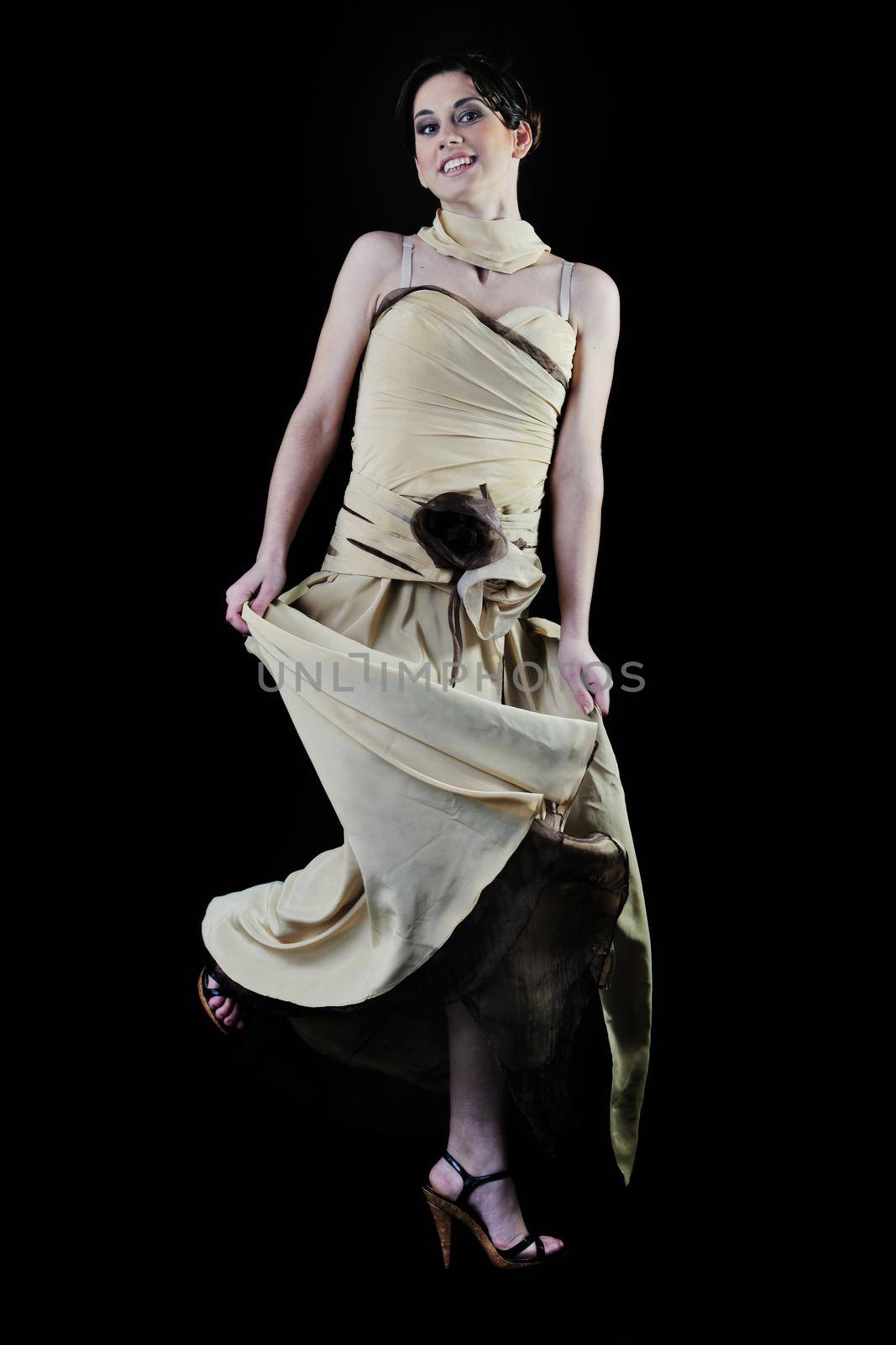  young woman in beautiful luxury dress in studio against black background in dark representing nightlife and fashion concept