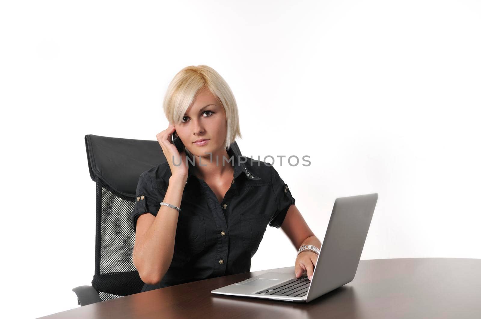 One young business blonde woman working in office on laptop and talking on cellphone, isolated image