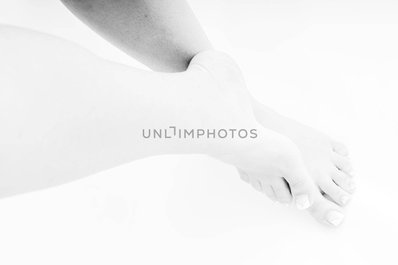 young woman bare foot with makeup nails islated on white