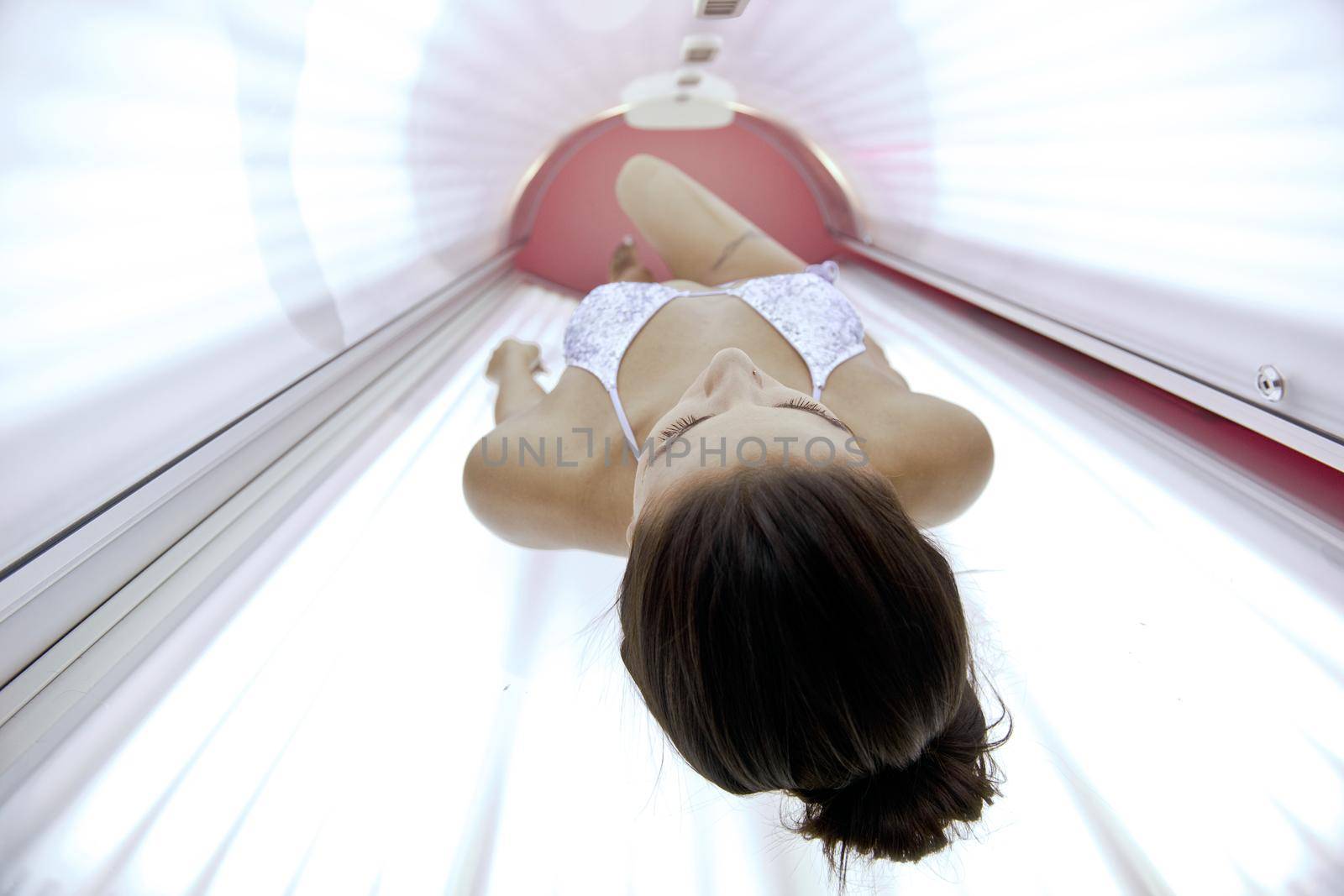 Beautiful young woman tanning in solarium by dotshock