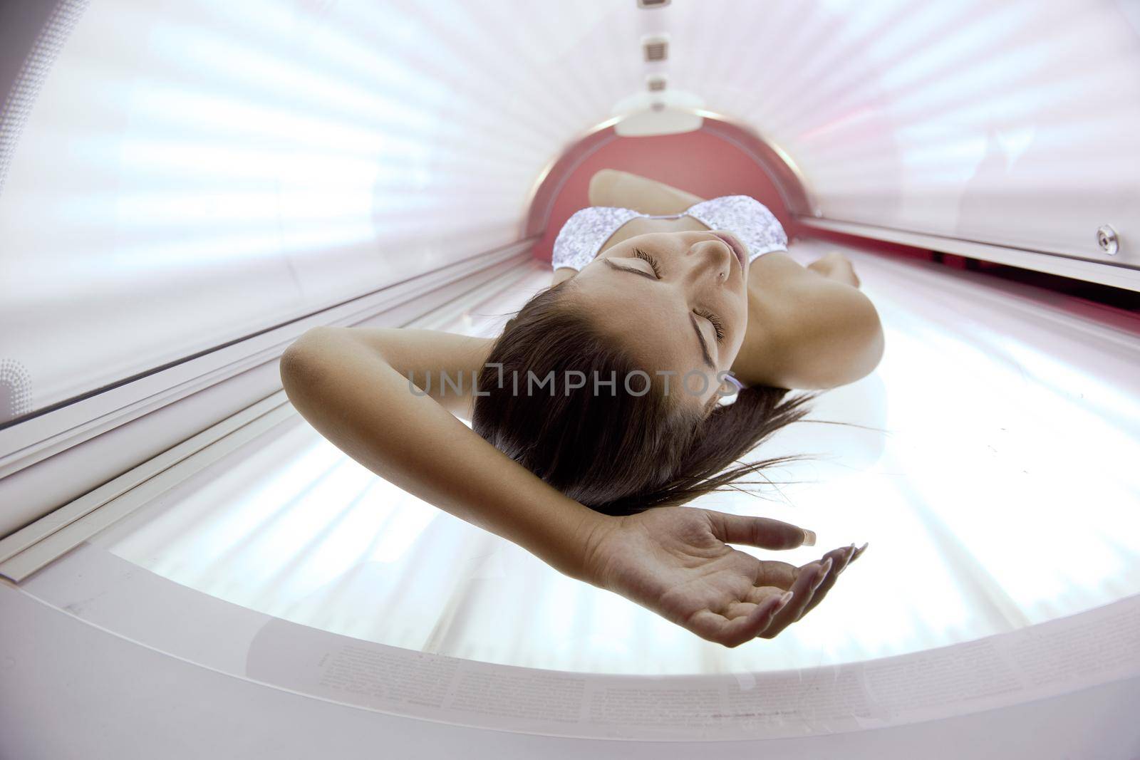 Beautiful young woman tanning in solarium by dotshock