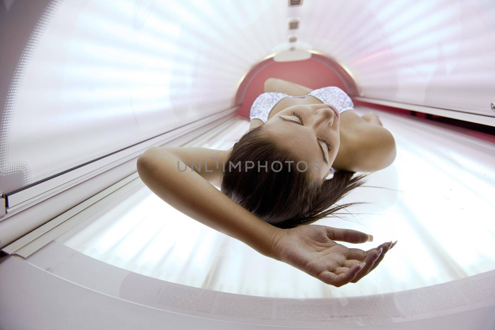 Beautiful young woman have tanning skin treatment in modern solarium