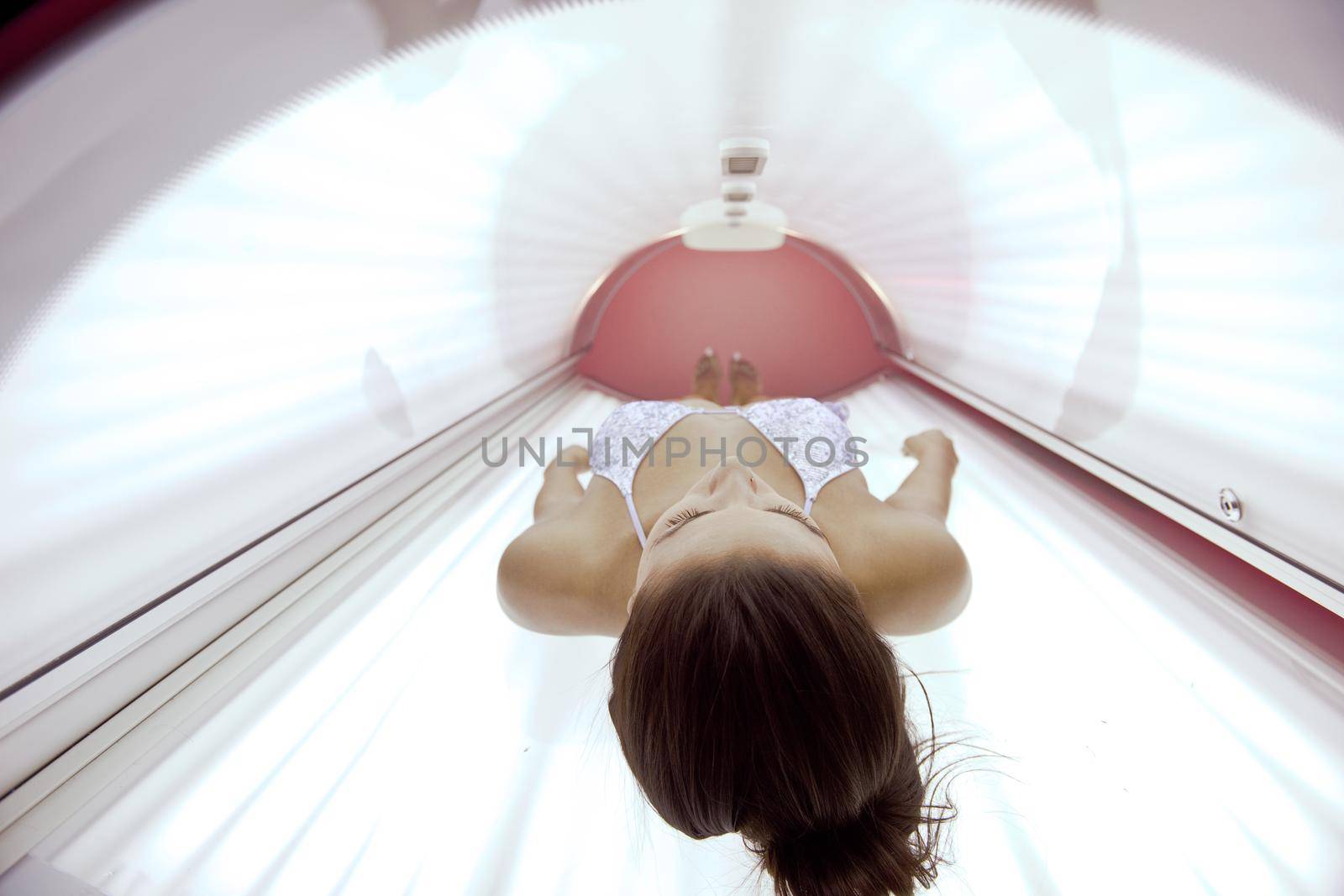 Beautiful young woman tanning in solarium by dotshock