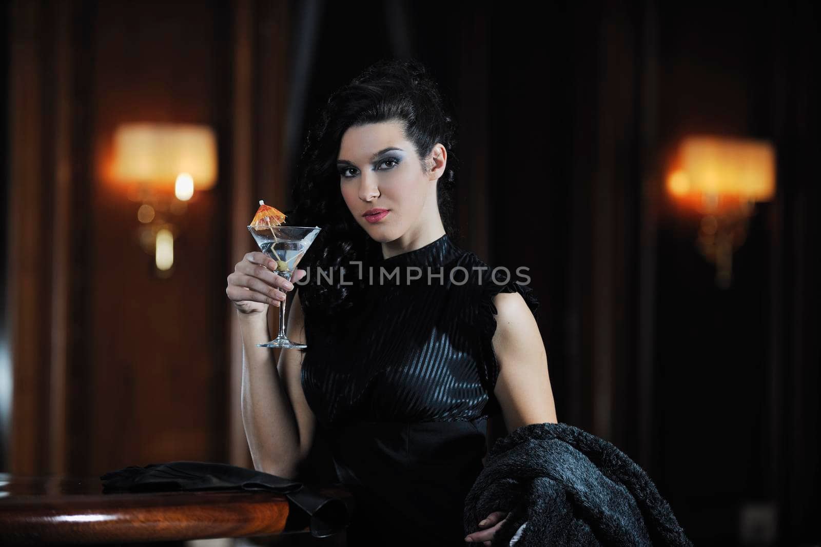 young happy lady in bar restaurant at night drinking martini