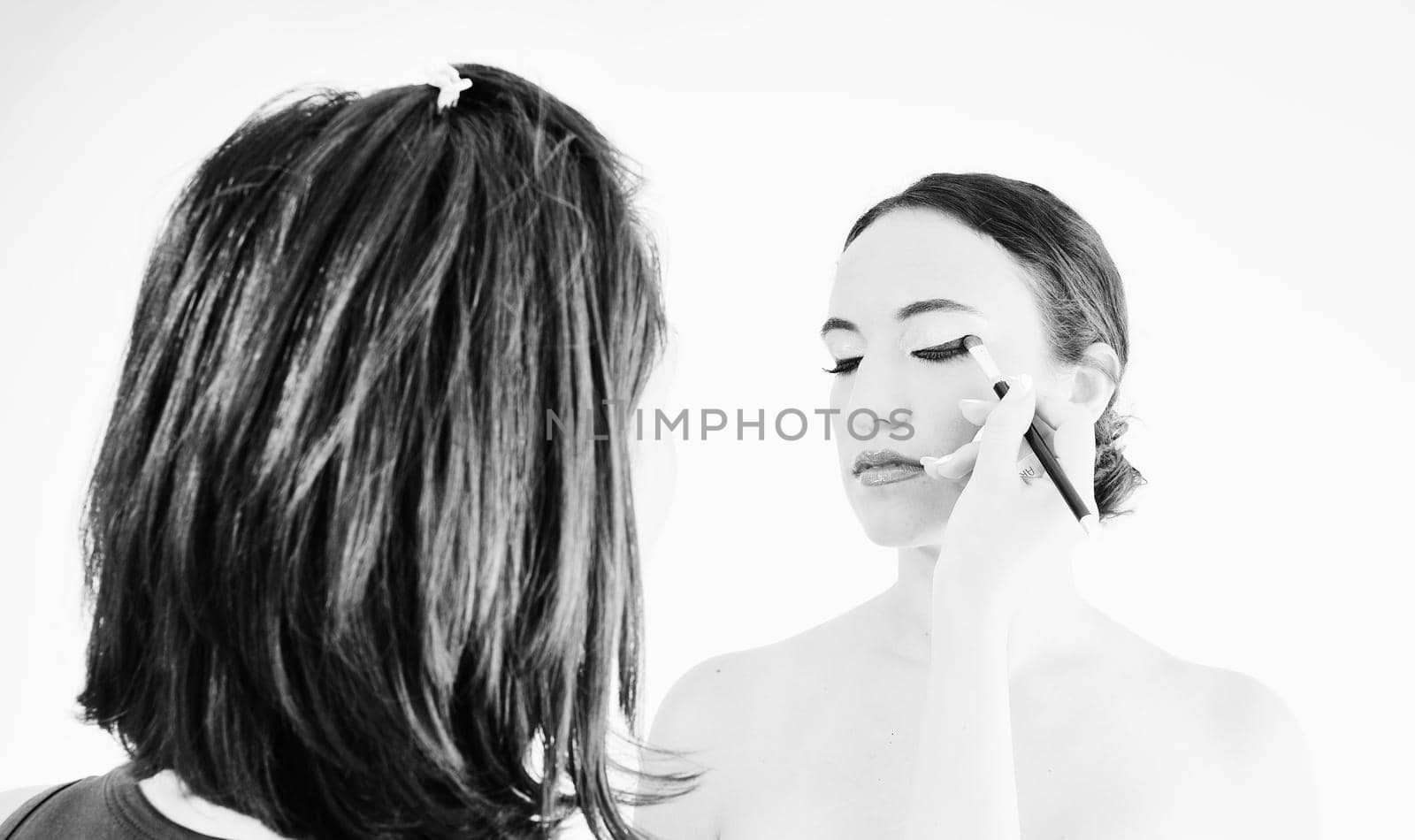 makeup treatment with professional makeup artist and beautiful brunette woman  isolated on white in studio