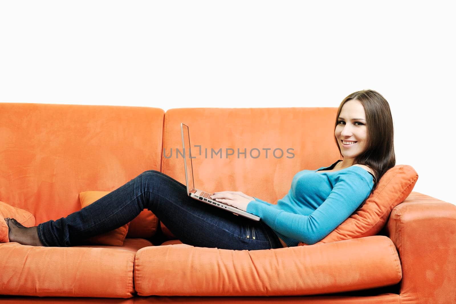 young business woman in casual clothes working on laptop computer on orange sofa isolated on white