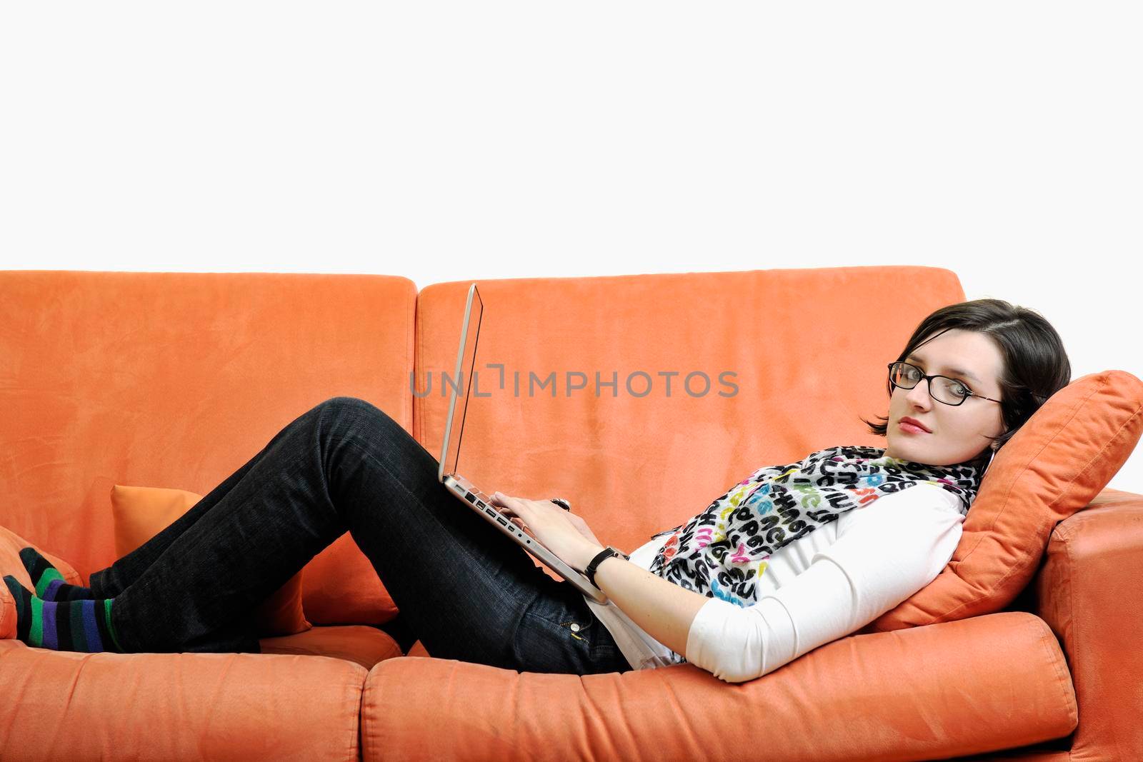 young business woman in casual clothes working on laptop computer on orange sofa isolated on white