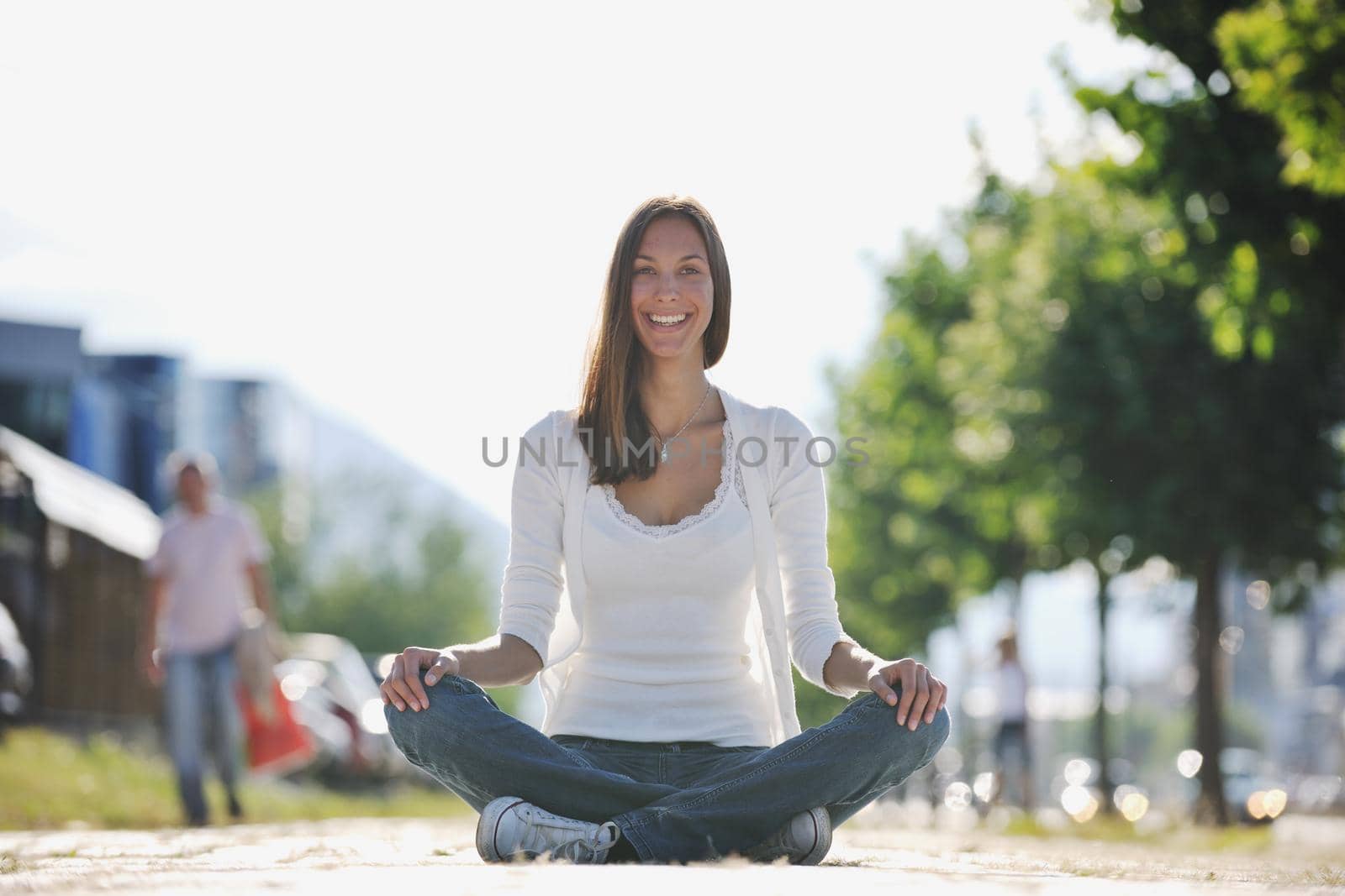 beautiful young woman meditating and exercise yoga in lotus position at street at beautiful sunny day with blured background