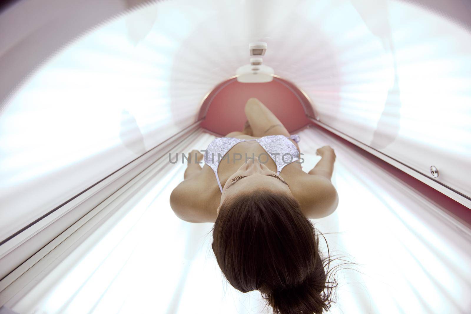 Beautiful young woman have tanning skin treatment in modern solarium