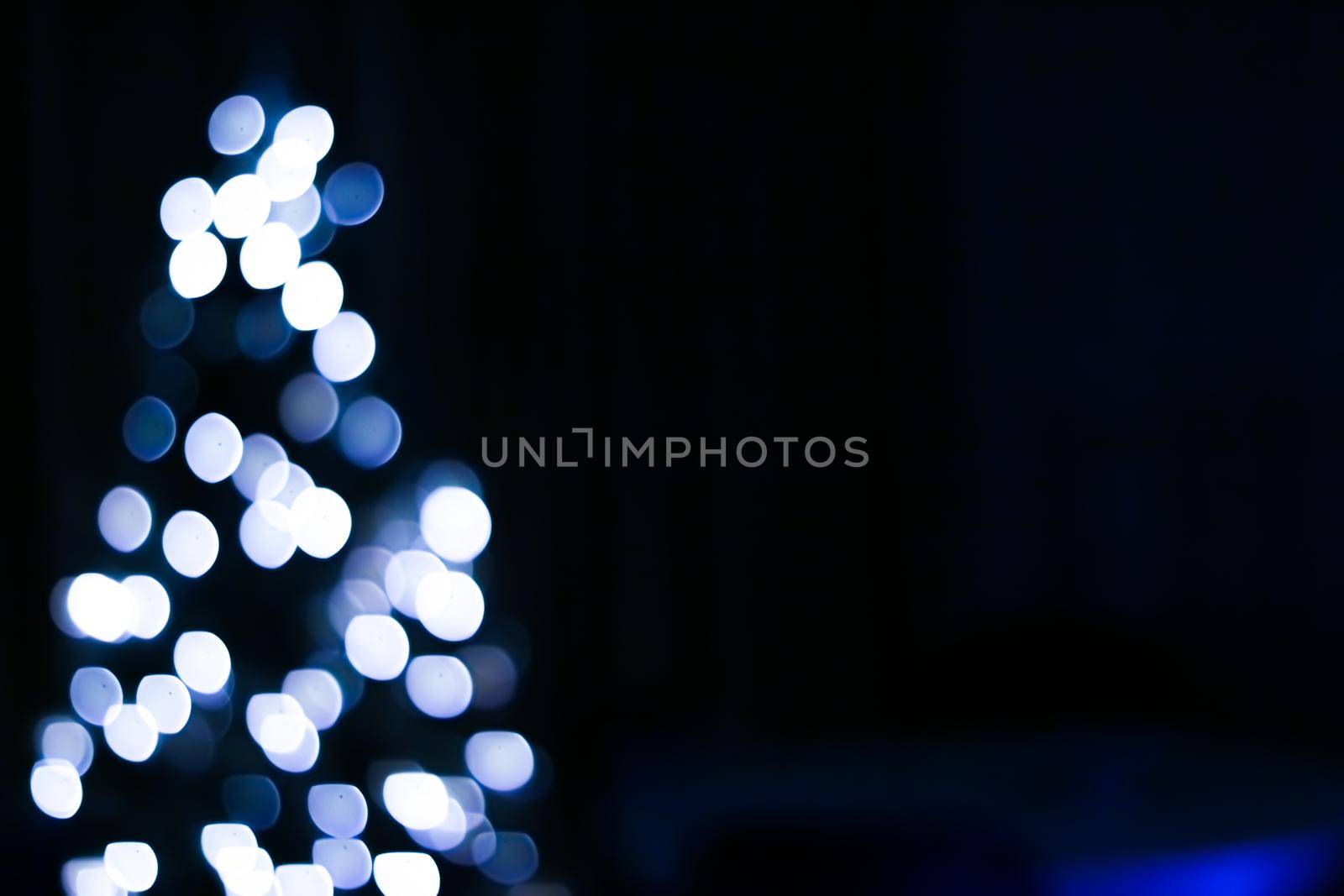 Christmas time and holiday mood concept. Blurred blue xmas tree lights as bokeh background.
