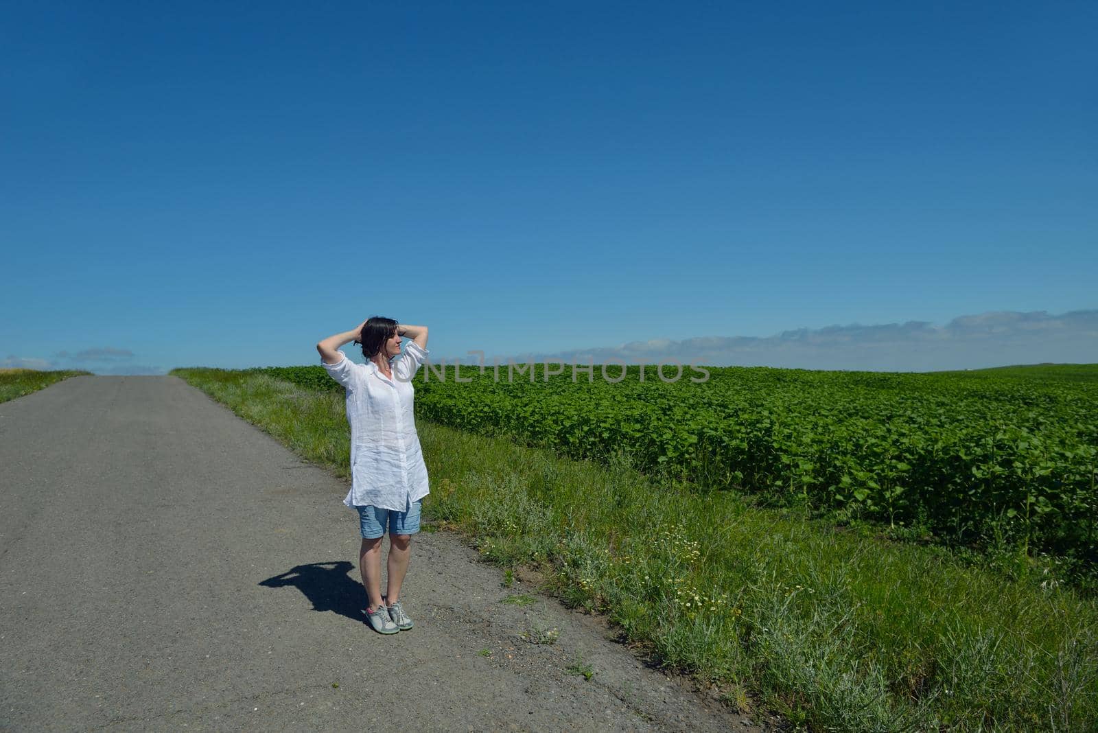 Young happy woman in green field with blue sky in background