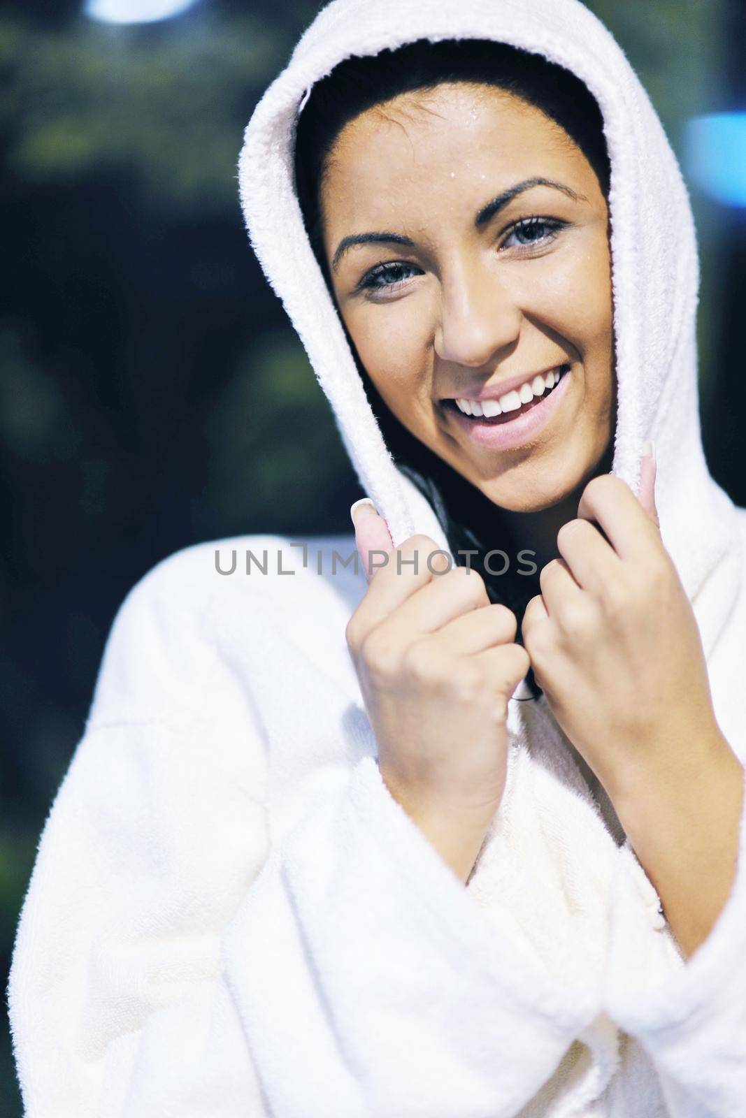 Pretty Young woman take a steam bath treatment at finish wooden sauna while wearing white towel