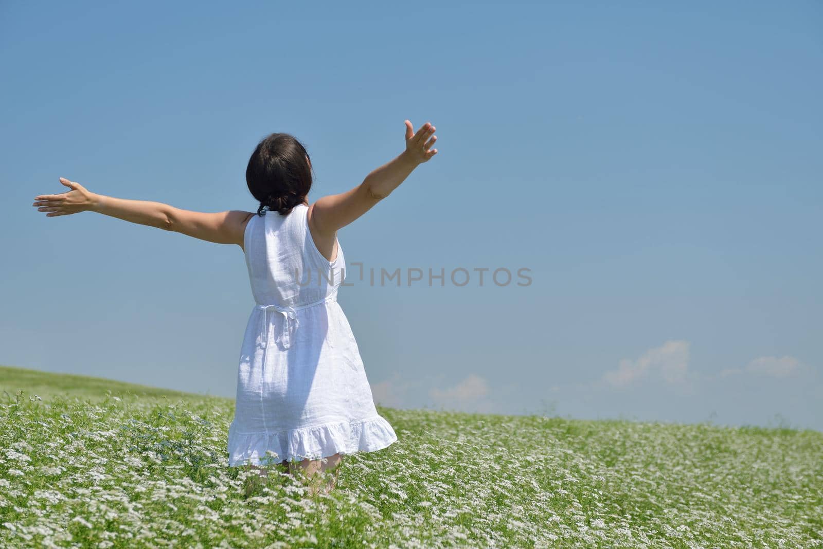 Young happy woman in green field with blue sky in background