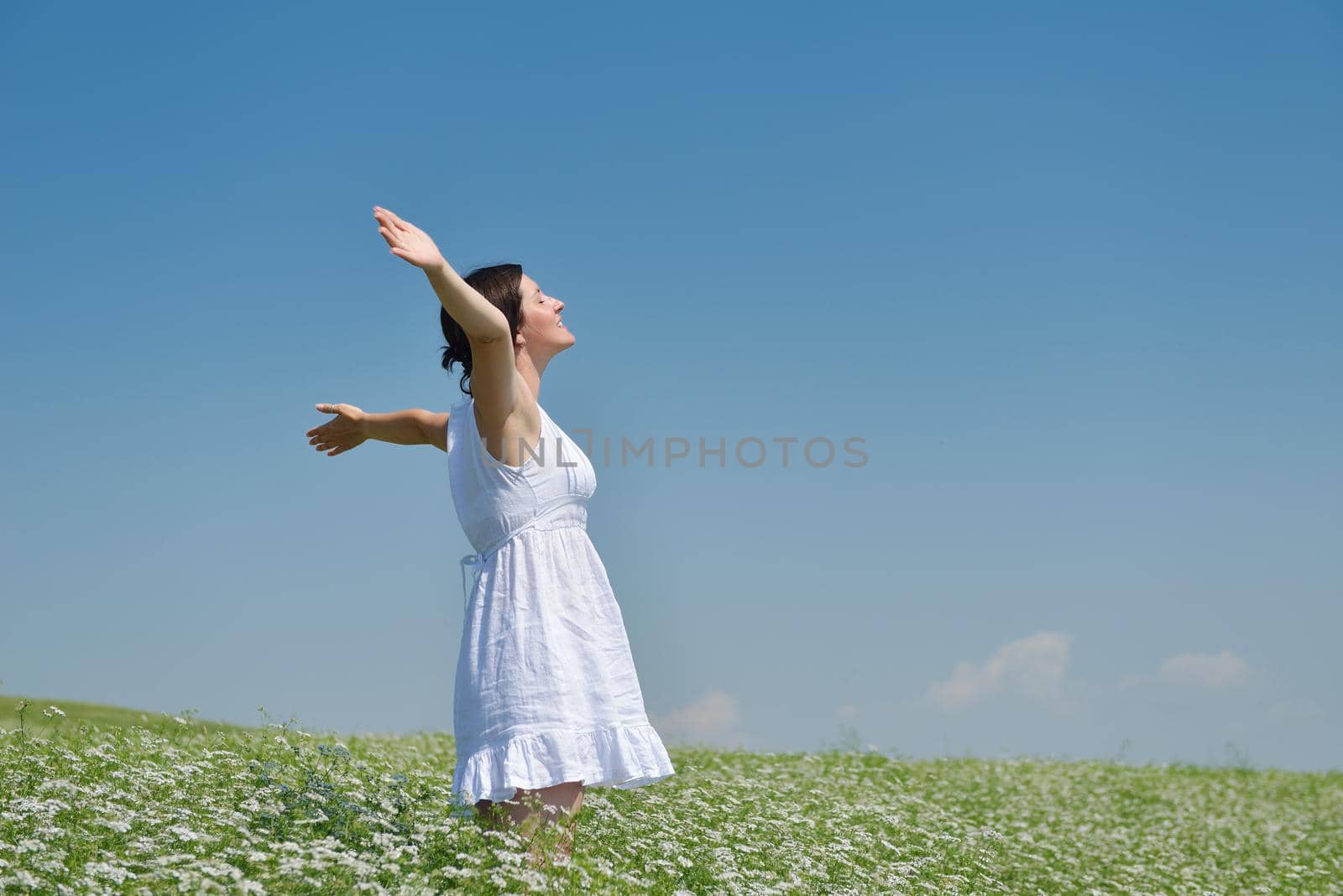 Young happy woman in green field with blue sky in background