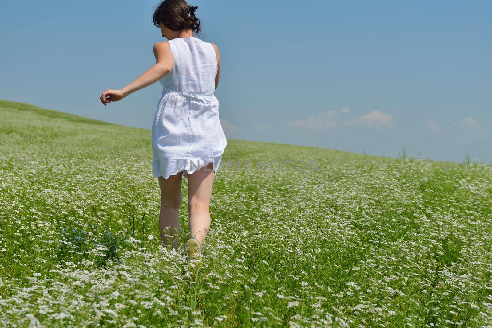 Young happy woman in green field with blue sky in background