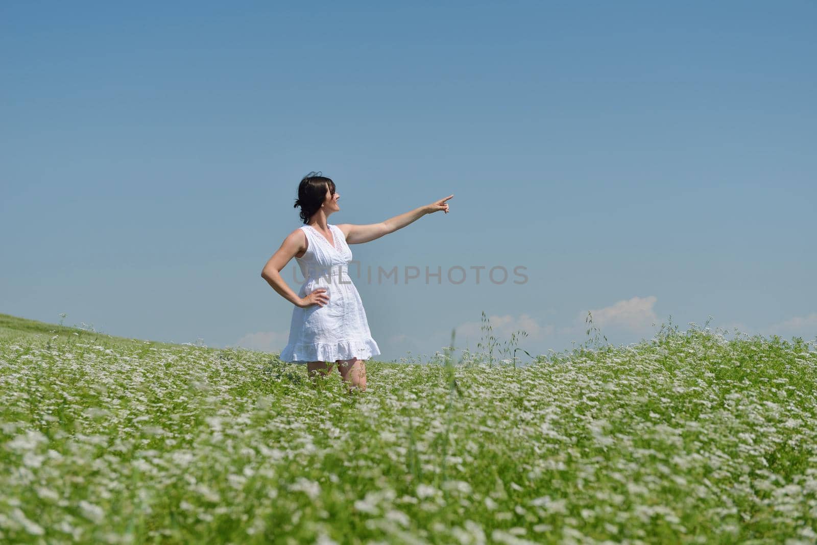 Young happy woman in green field with blue sky in background